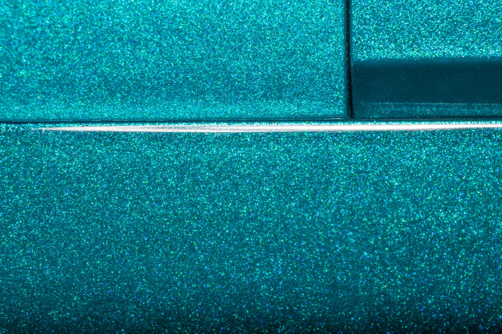 Surface d'une matière turquoise brillante avec une ligne blanche et un panneau rectangulaire en verre brillant.