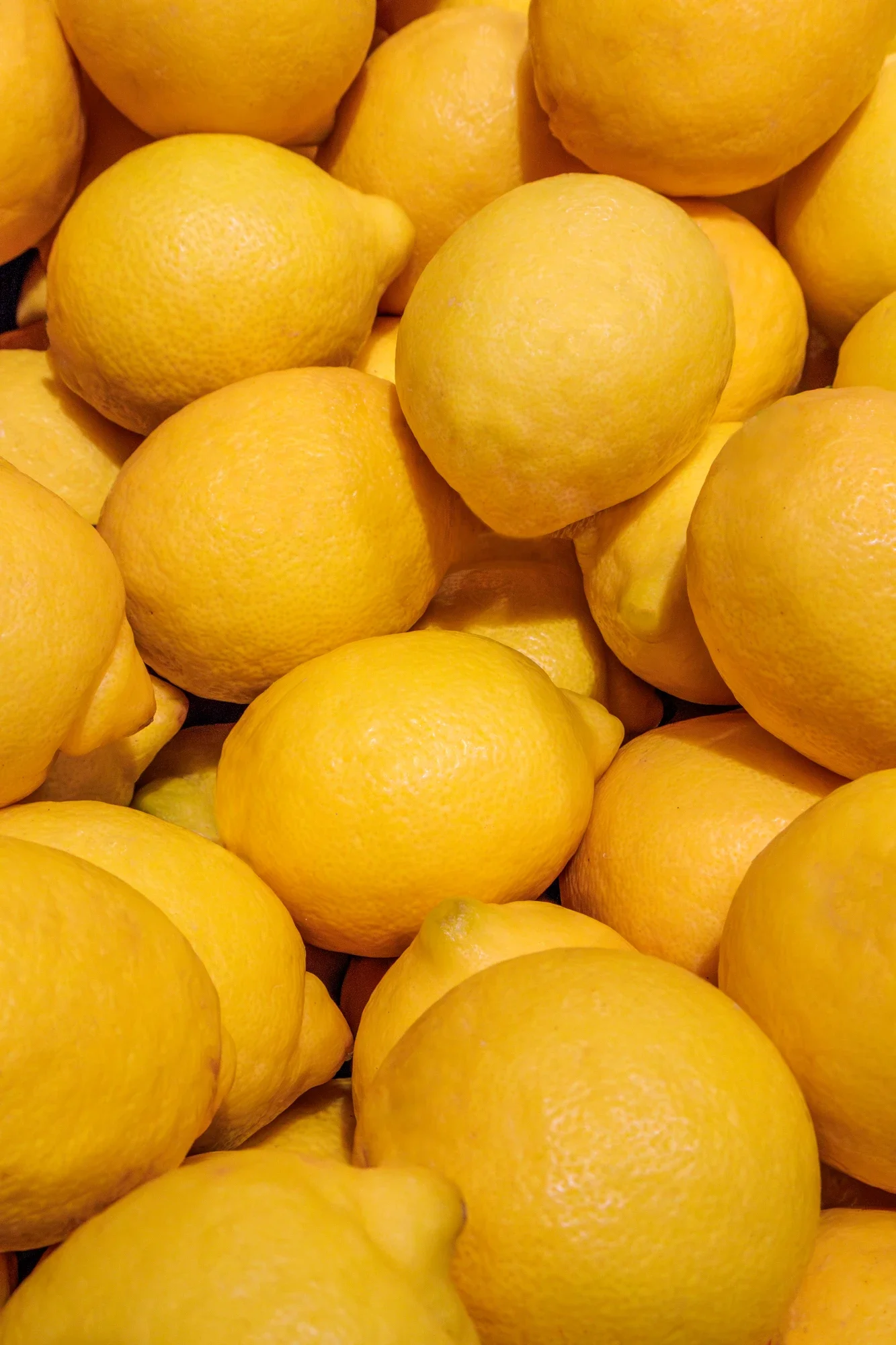 Une multitude de citrons jaunes empilés.