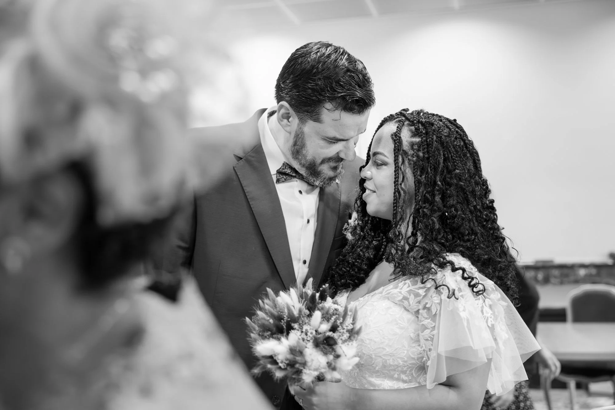 Un couple lors de leur mariage, se regarde tendrement, en noir et blanc.