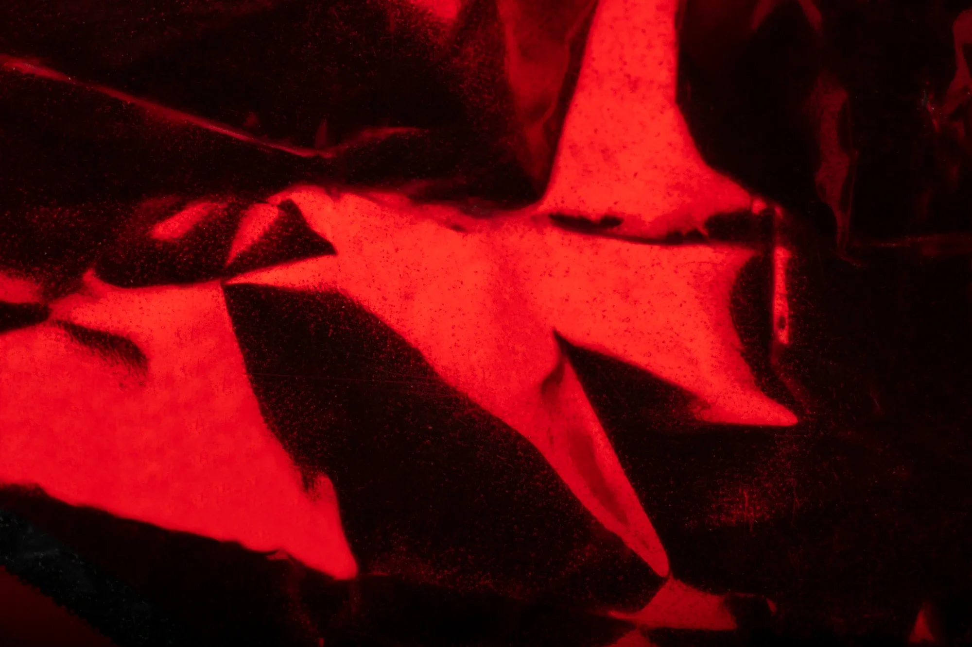 Une image abstraite en rouge et noir, avec des formes floues et des contours indéfinis.