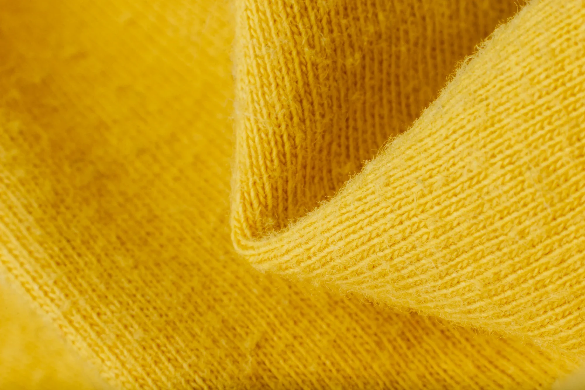 Gros plan d'un tissu jaune, montrant la texture et la maille.