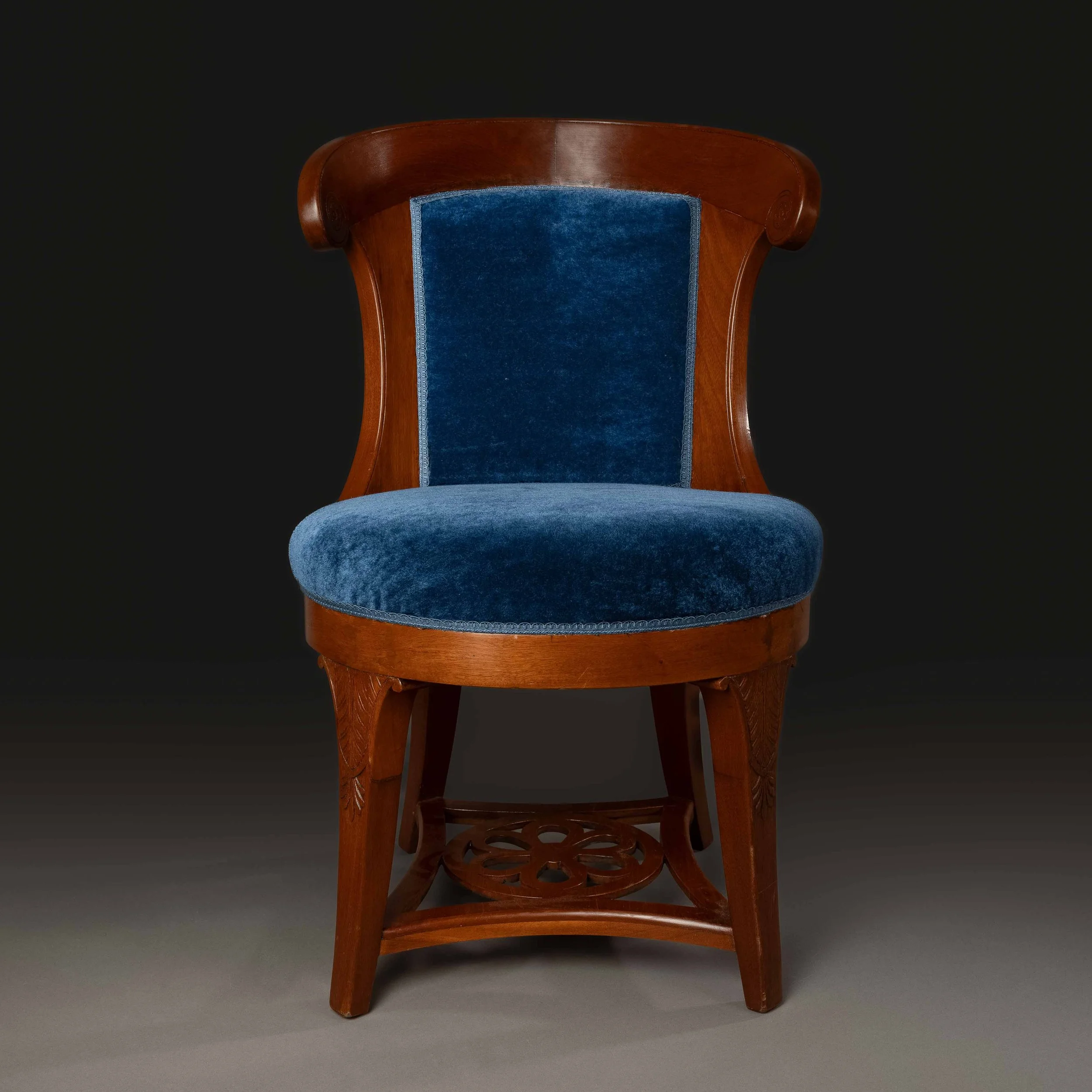 Chaise en bois avec assise et dossier en velours bleu, fond noir.