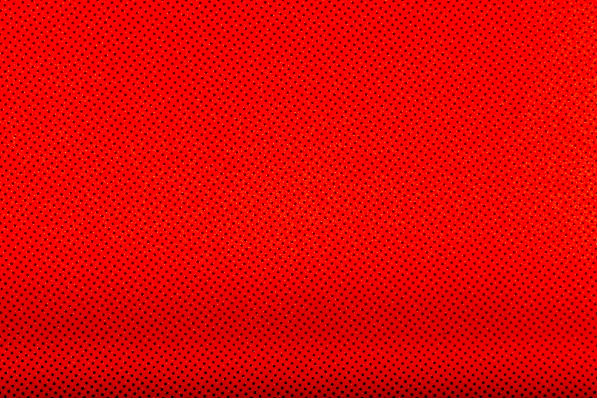 Une image rouge avec un motif de petits points noirs et jaunes répartis de manière régulière.