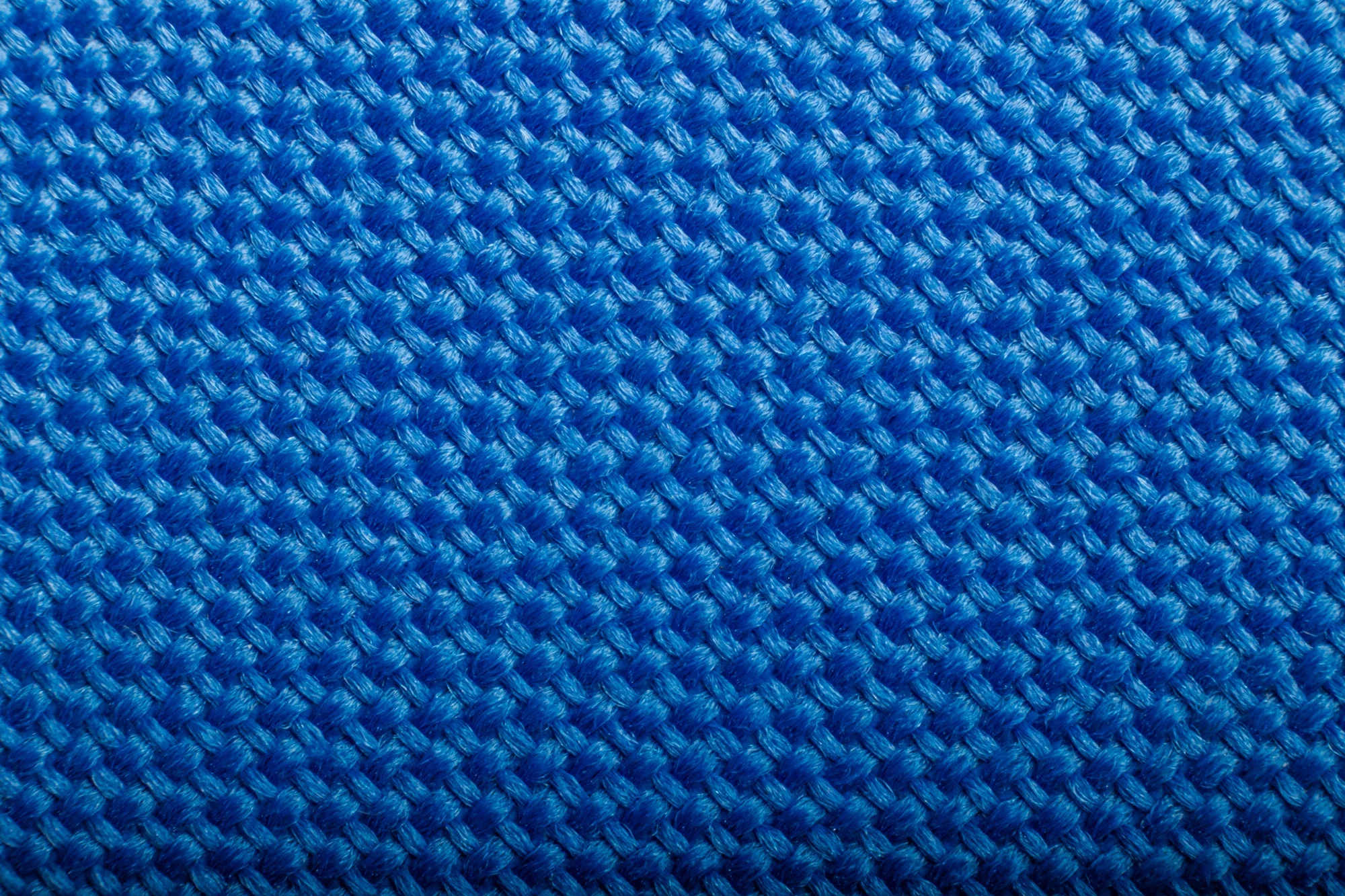Gros plan d'une surface en tissu bleu tissé de manière régulière.