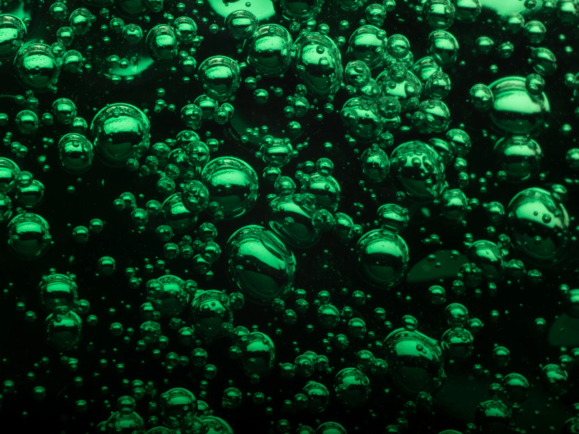 Une multitude de bulles vertes flotant dans un liquide, créant un motif abstrait.