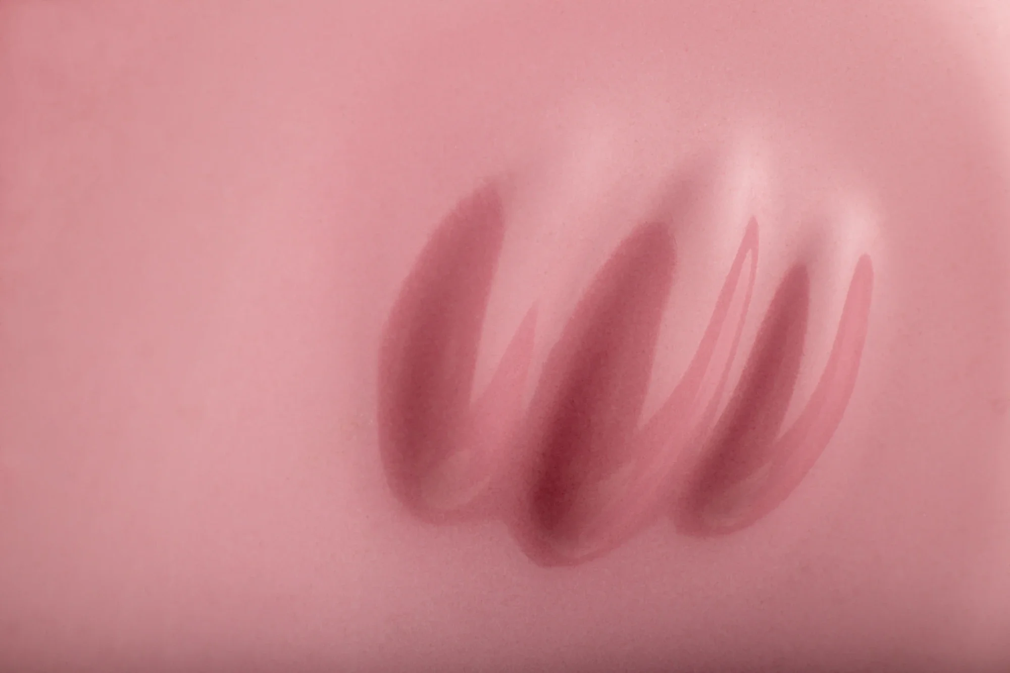 Une main posée sur une surface rose.