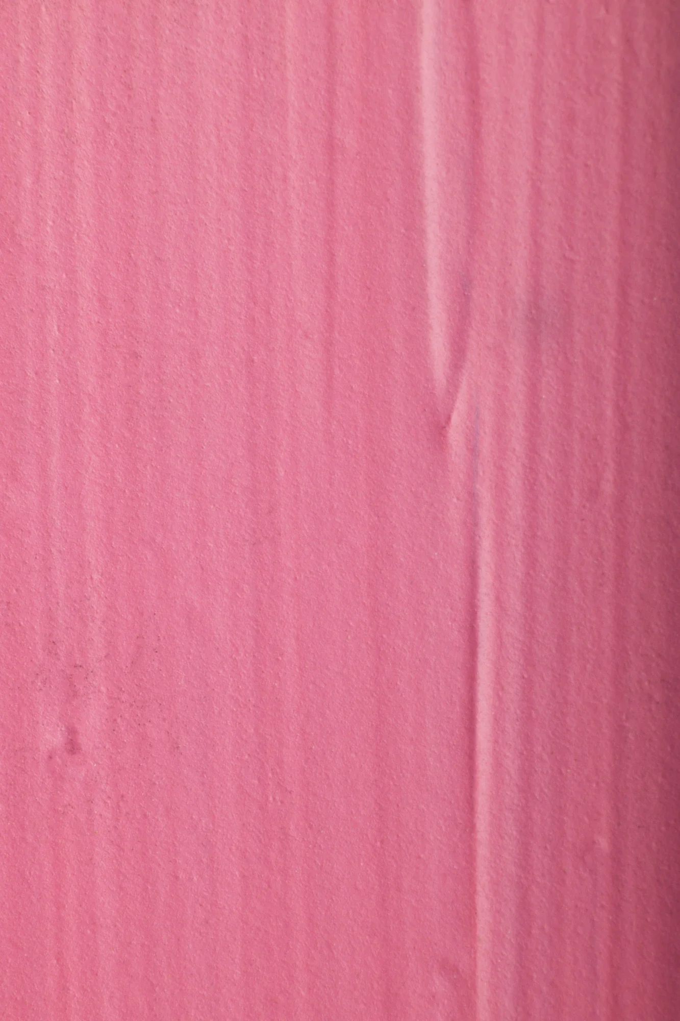 Surface en papier ou en tissu rose avec une texture légèrement froissée.