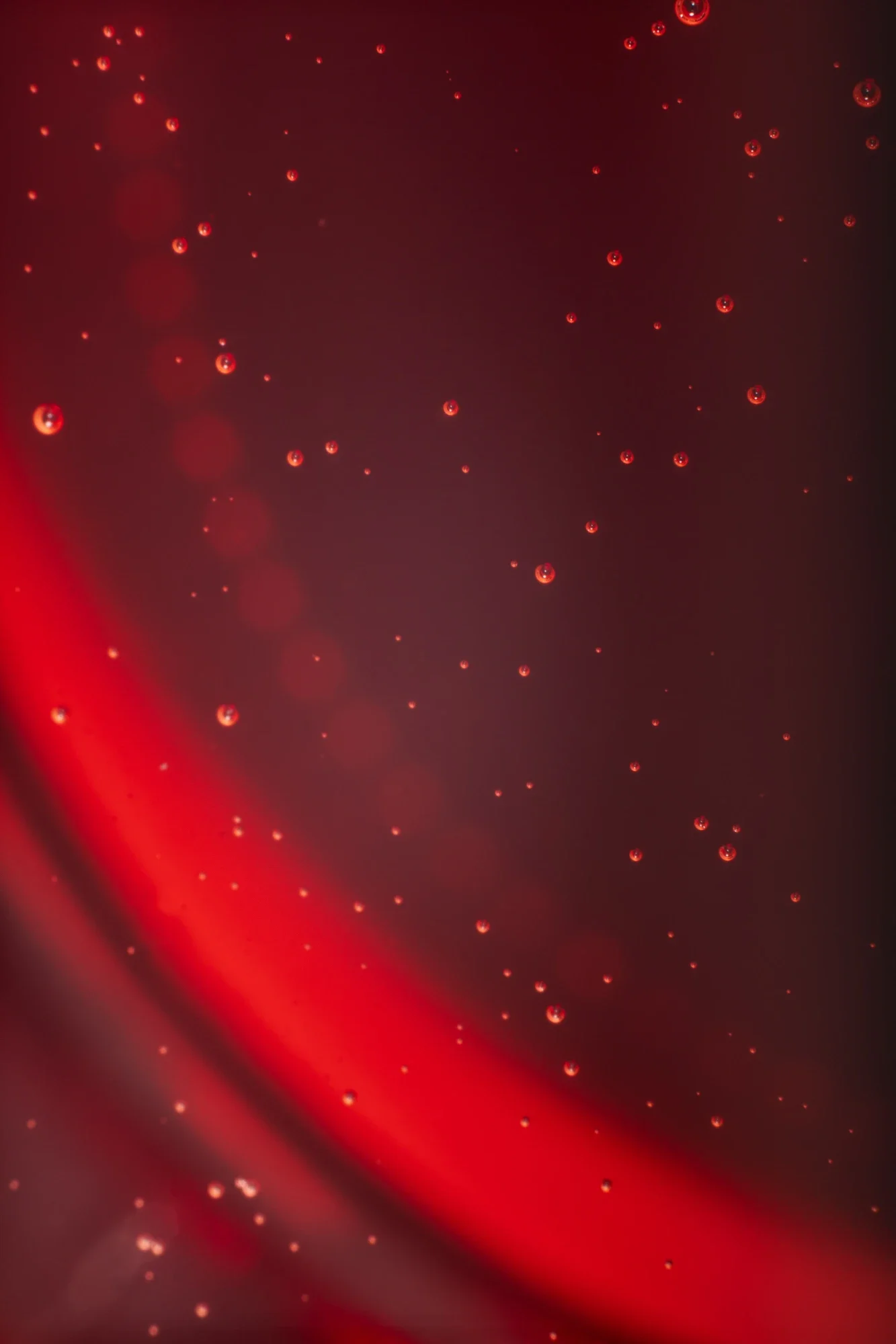 Gouttelettes d'eau suspendues dans un liquide rouge.