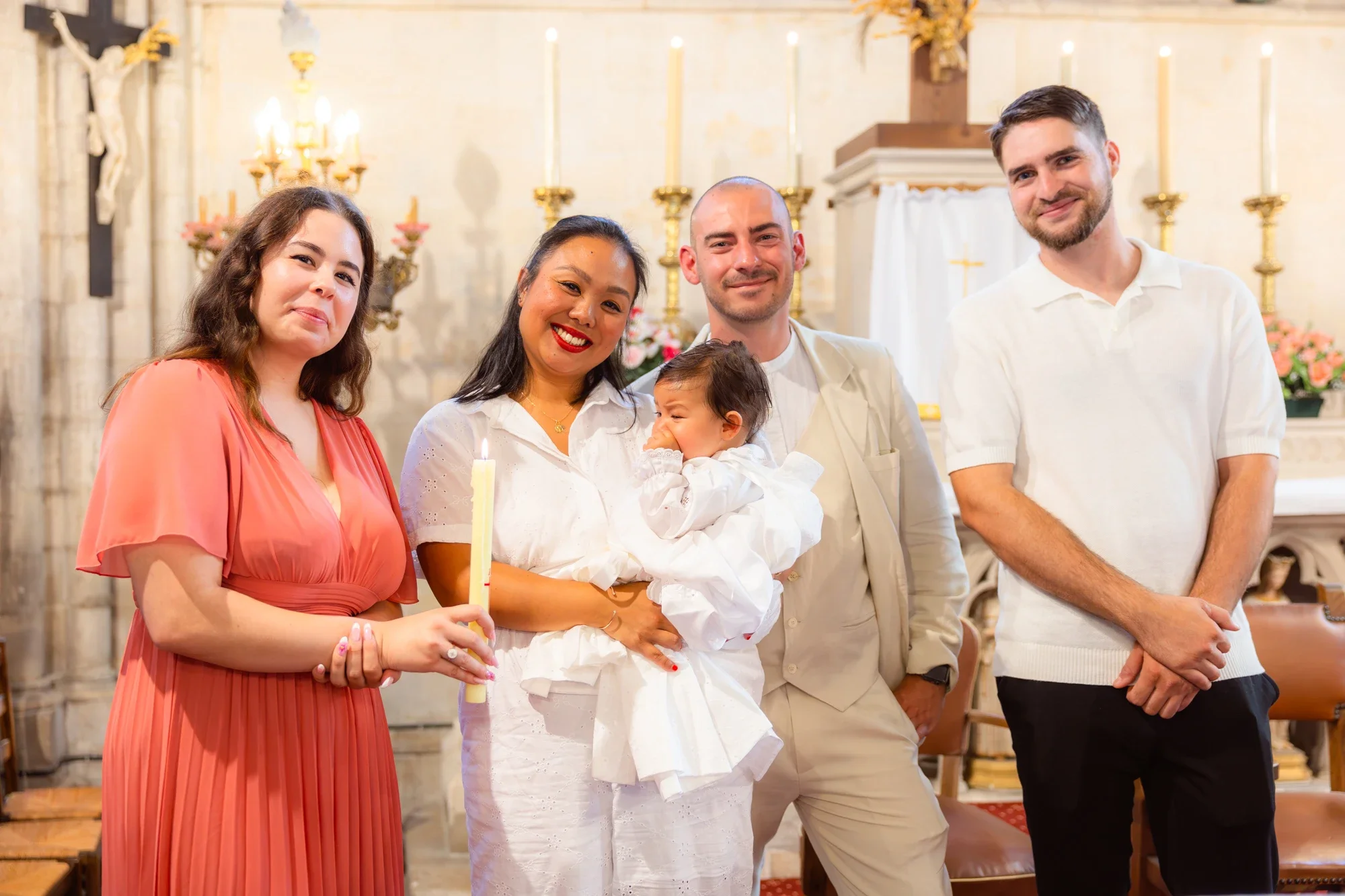 Groupe de cinq personnes lors d'une cérémonie religieuse dans une église, avec des bougies et la croix en arrière-plan.