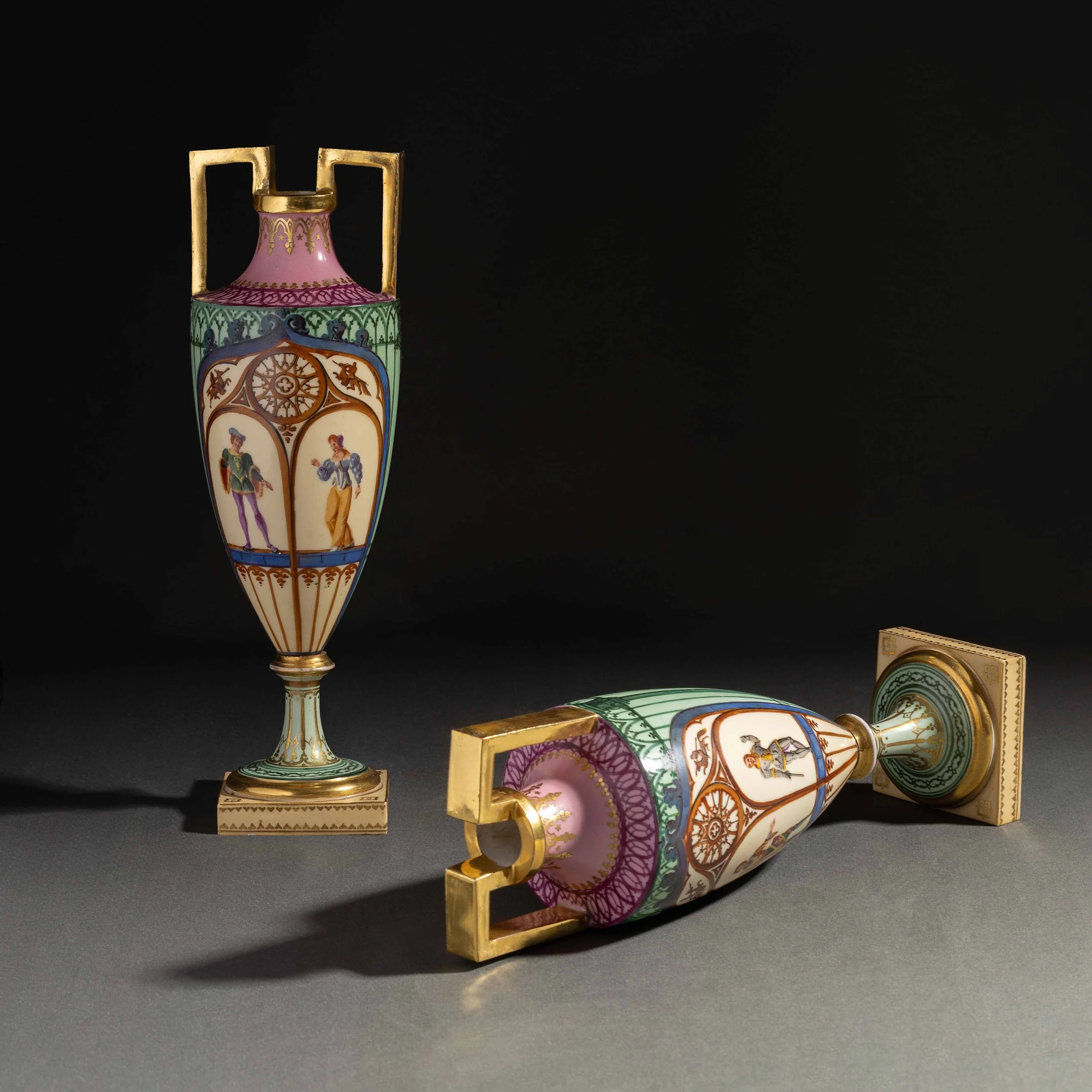Une collection de porcelaines décoratives colorées, comprenant une vase, un theière, une boîte et une coupelle, ornées de motifs et de personnages, disposée sur une surface noire.