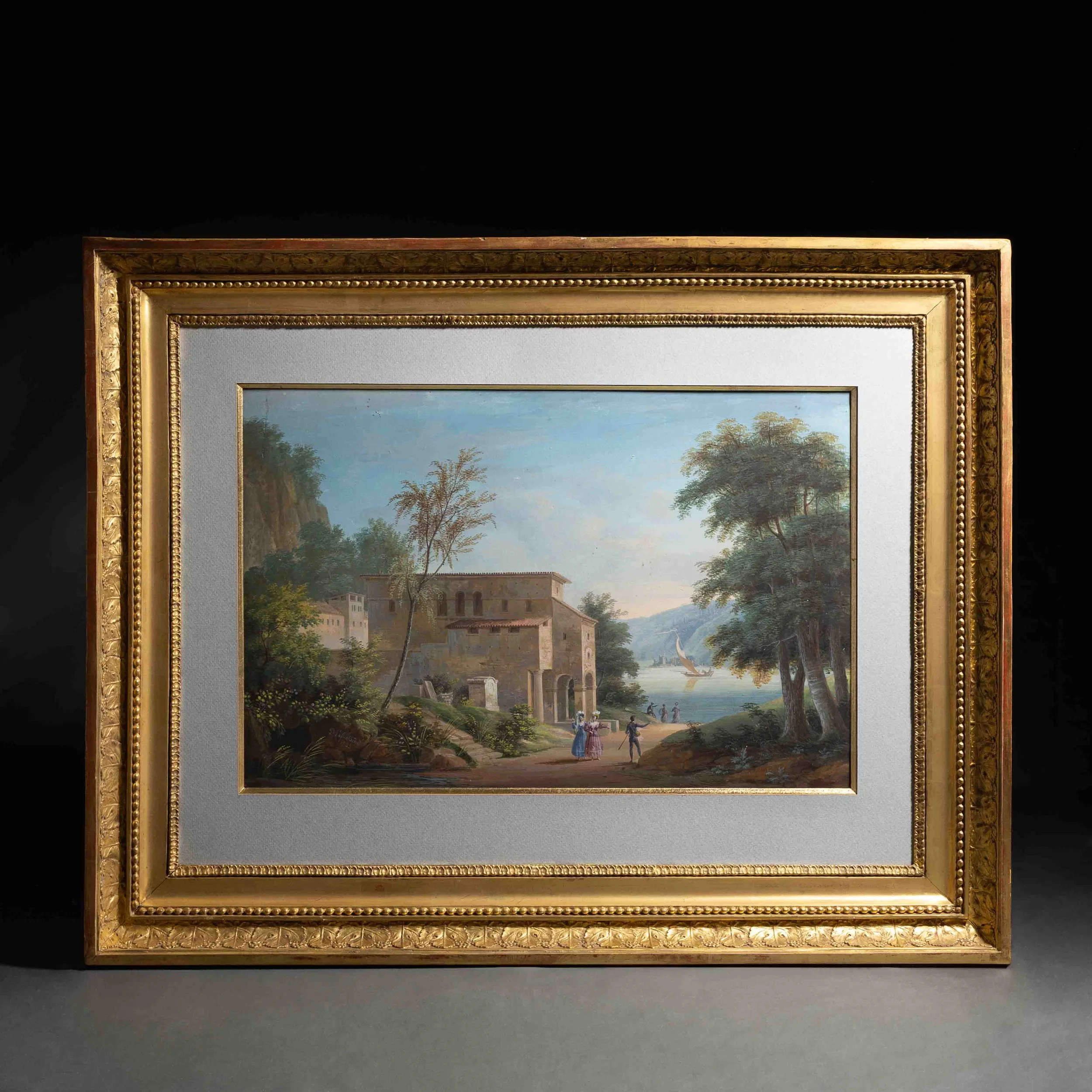 Cadre doré contenant une peinture représentant une scène de paysage avec des arbres, une rivière et un ciel bleu, posé contre un mur noir.