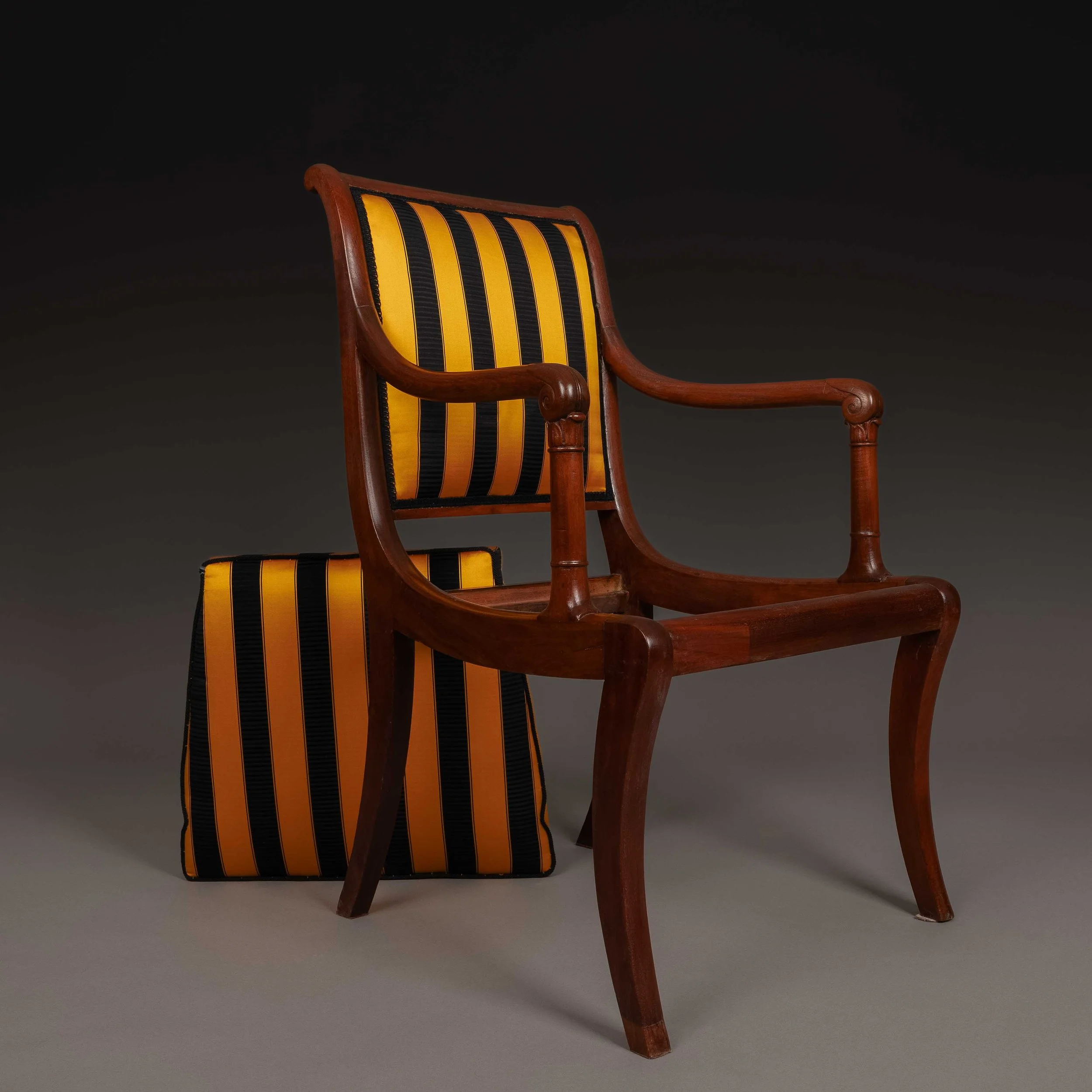 Une chaise en bois avec un siège et un dossier rembourrés à rayures jaunes et noires, vue partielle.