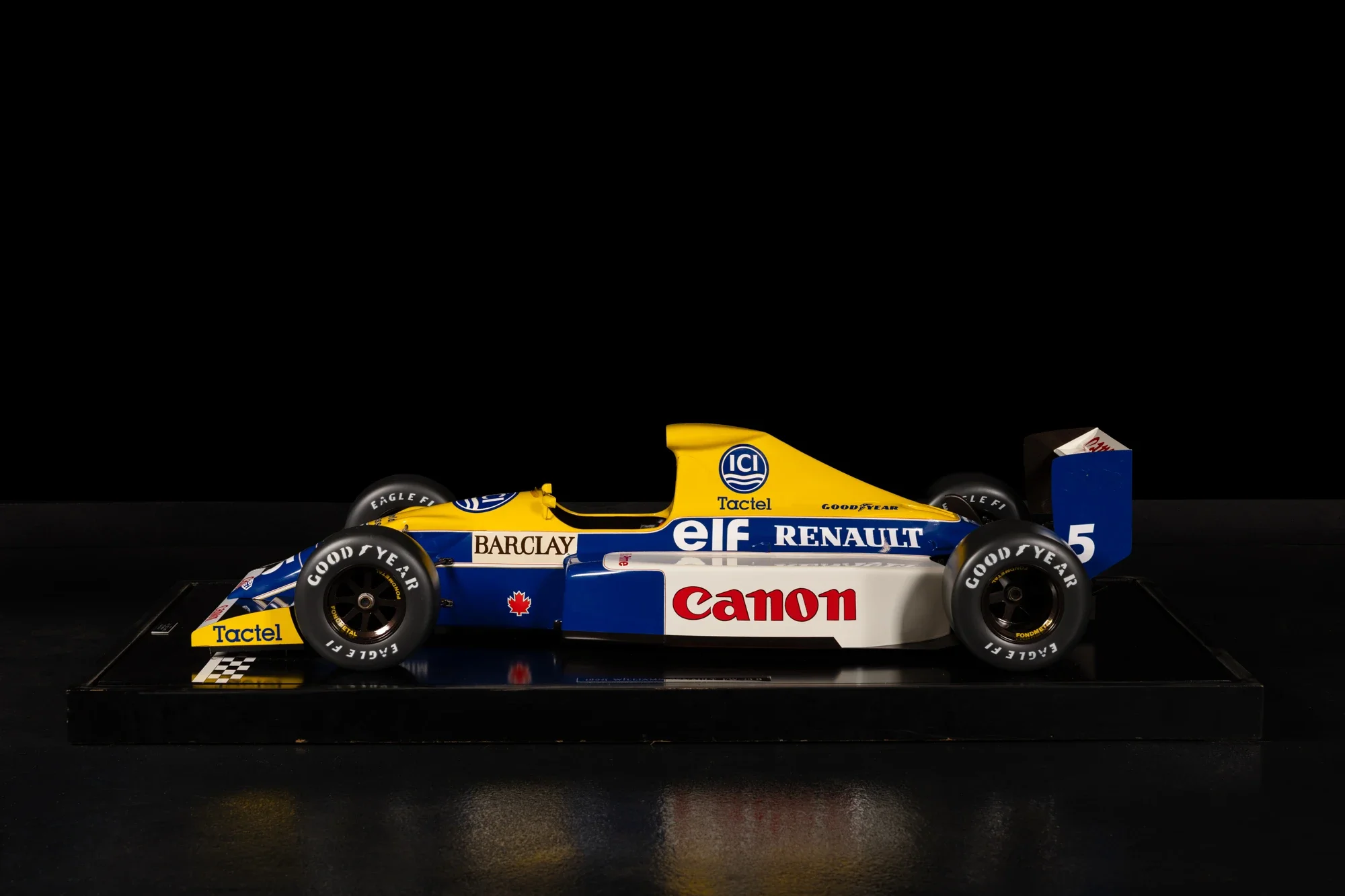 Voiture de course Renault dans une vitrine avec logos Canon, ELF, Goodyear, Barclays, Tactel, et Canadian, sur une plaque de base noire