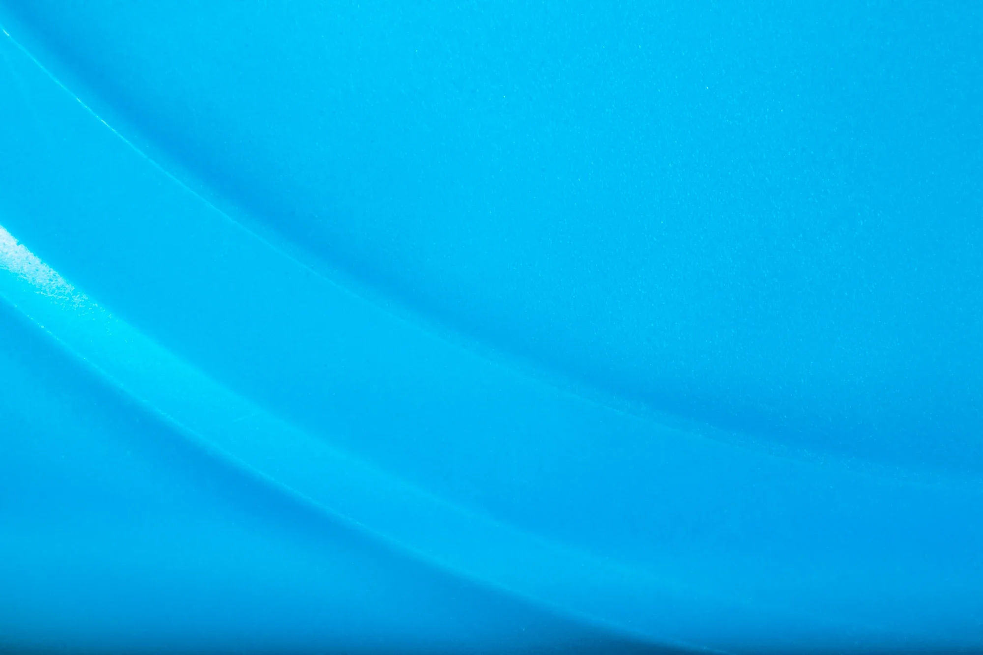 Surface en plastique ou en caoutchouc de couleur bleue avec des reflets lumineux et des textures légèrement granuleuses.