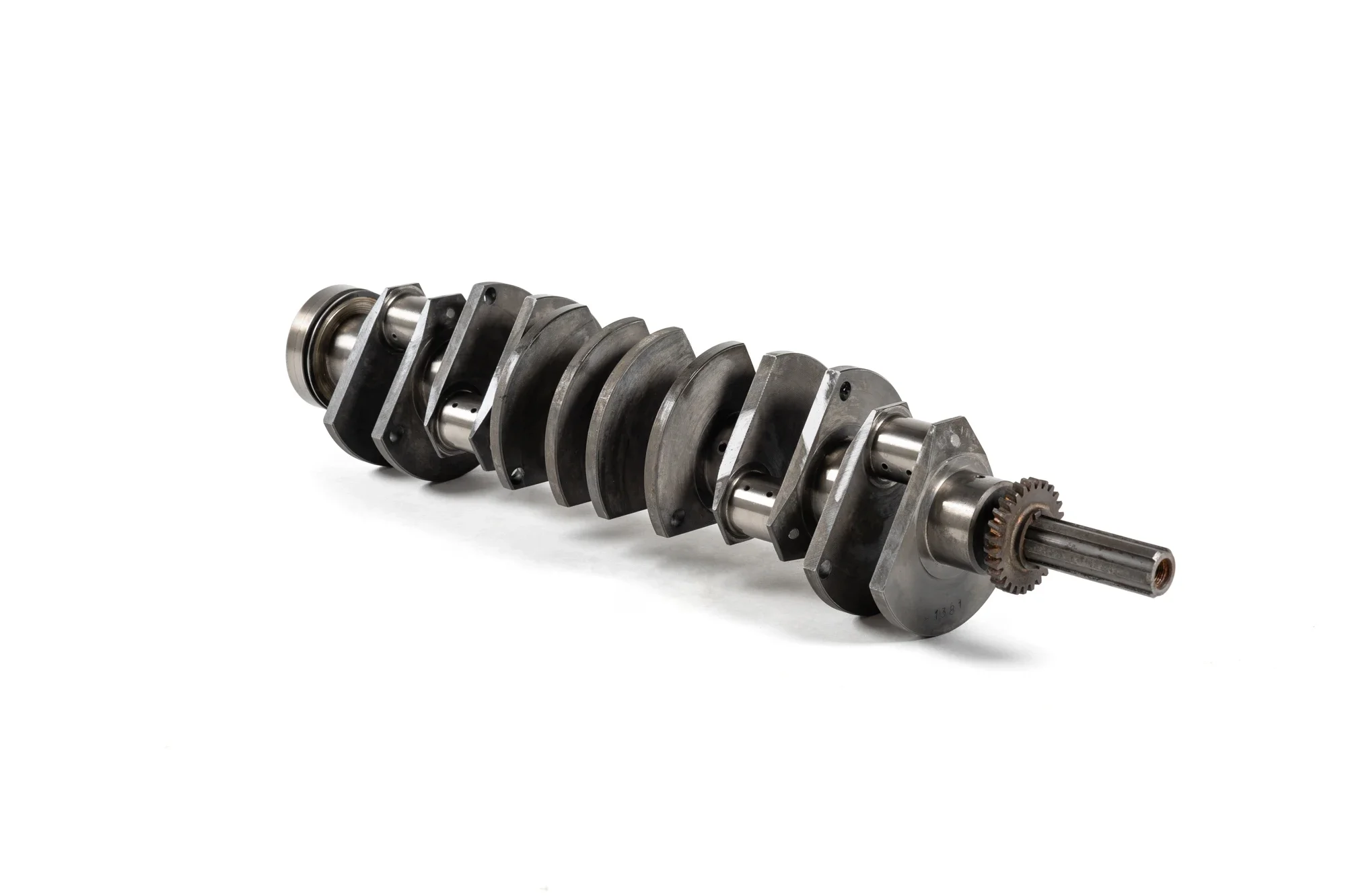 Un piston de moteur en métal, posé horizontalement, avec plusieurs segments et pièces mécaniques visibles.