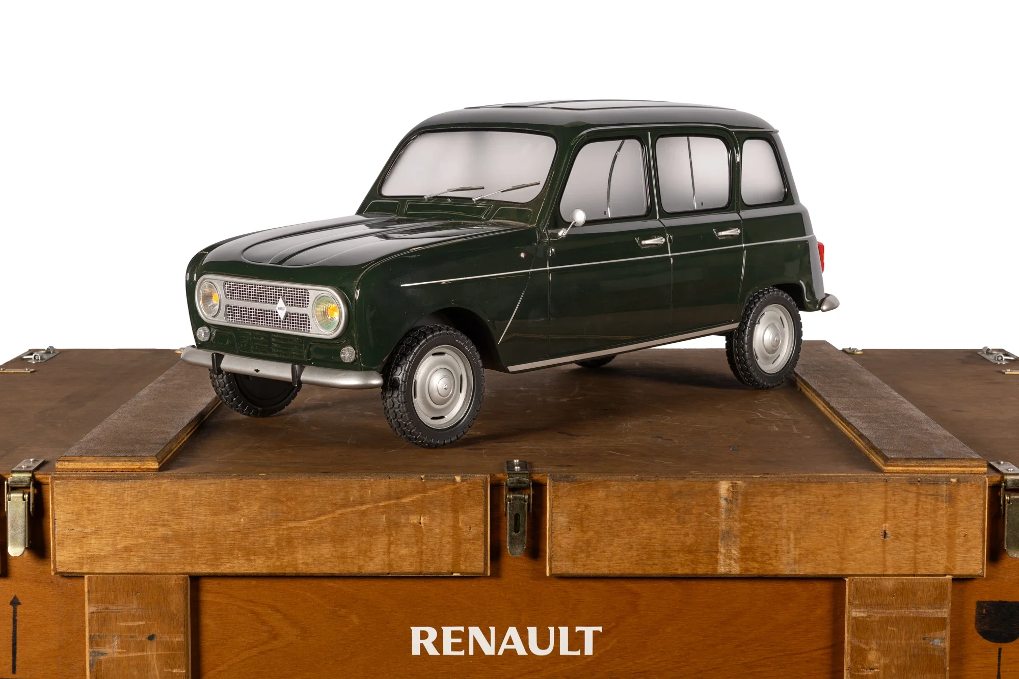 Une petite voiture ancienne de couleur verte sur une plateforme en bois avec une inscription "RENAULT".
