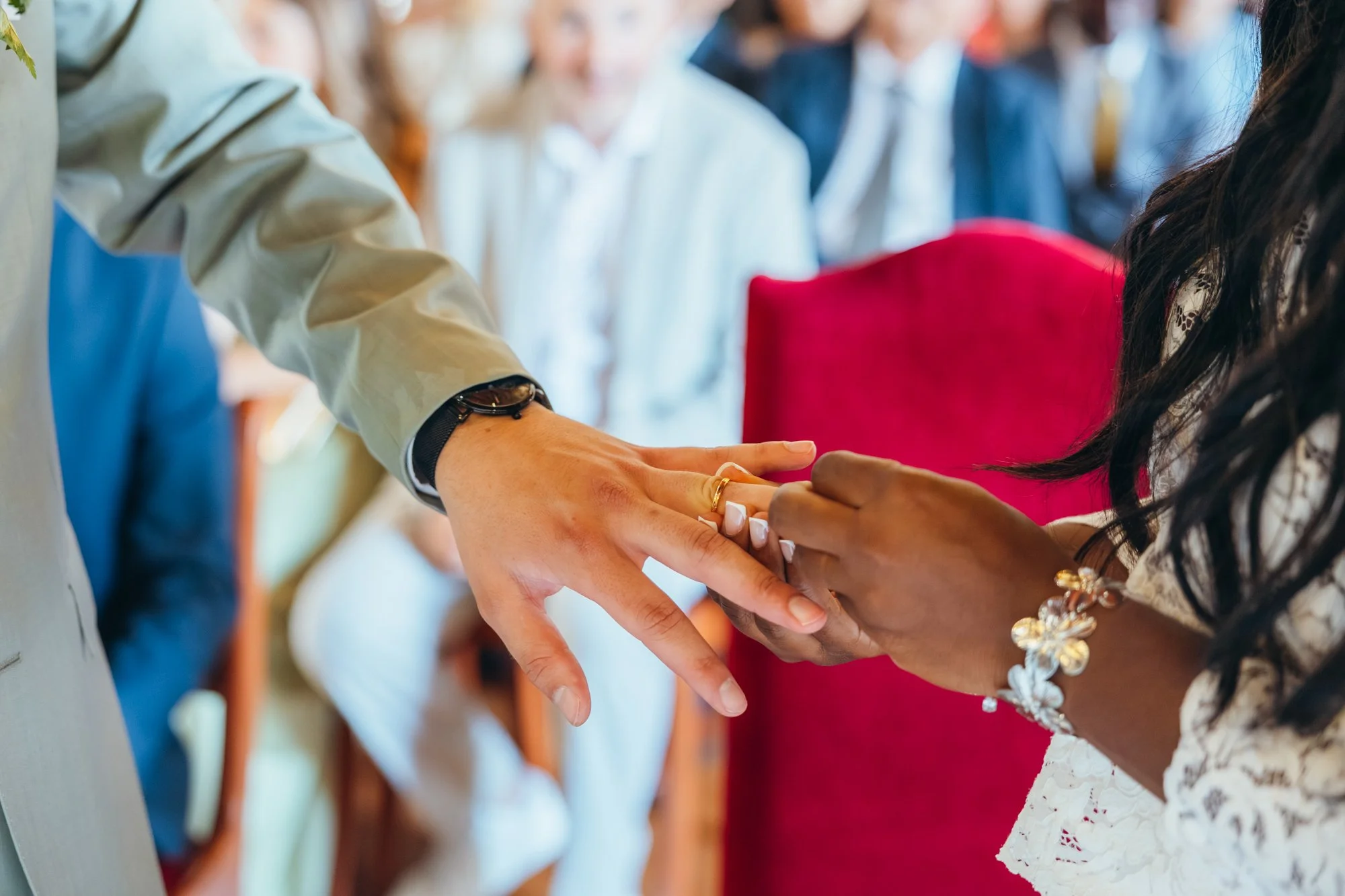 Une cérémonie de mariage où deux personnes échangent leurs alliances, entourées d'invités.