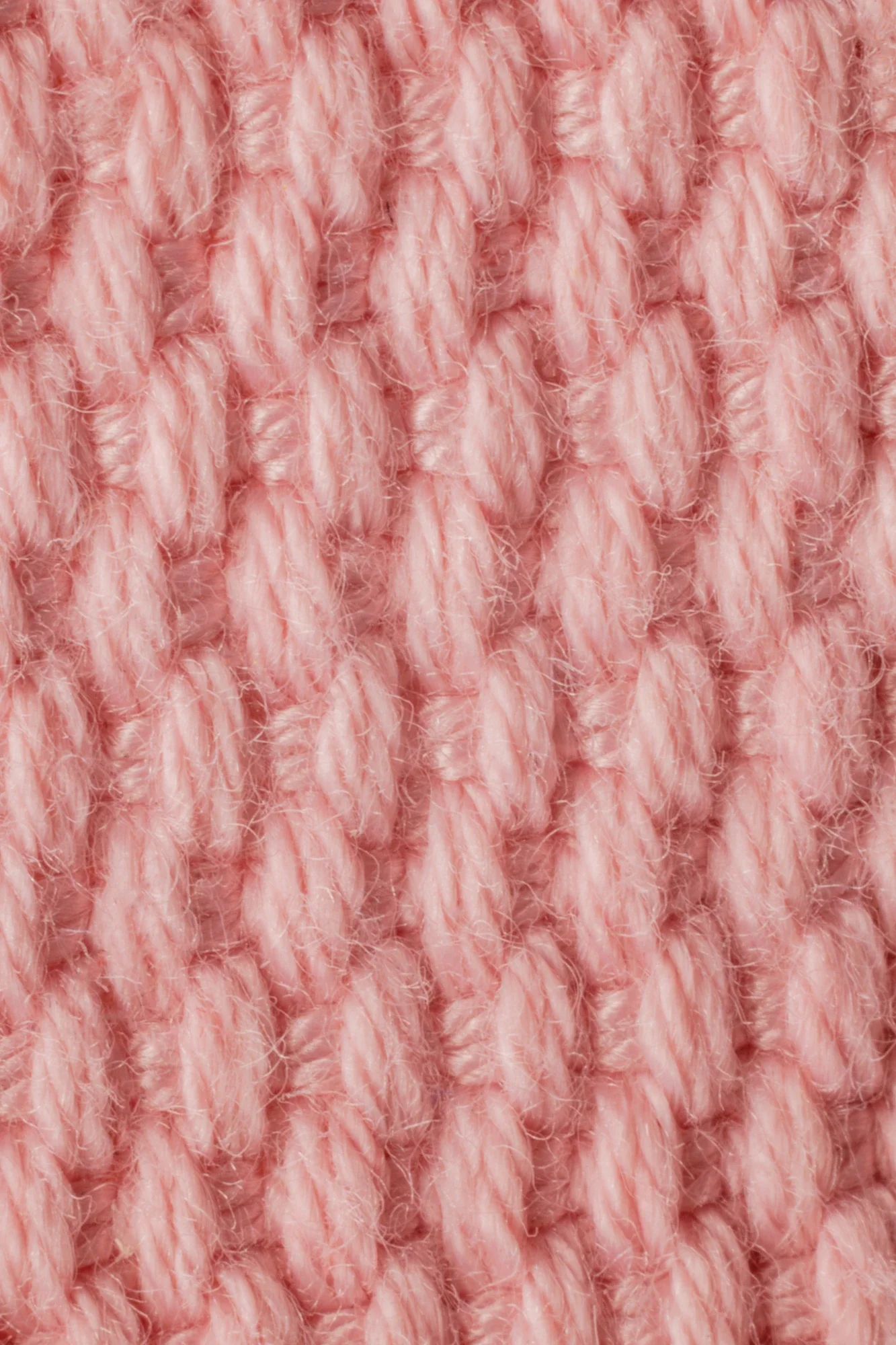 Gros plan sur un tissu en laine de couleur rose avec un motif en torsade.