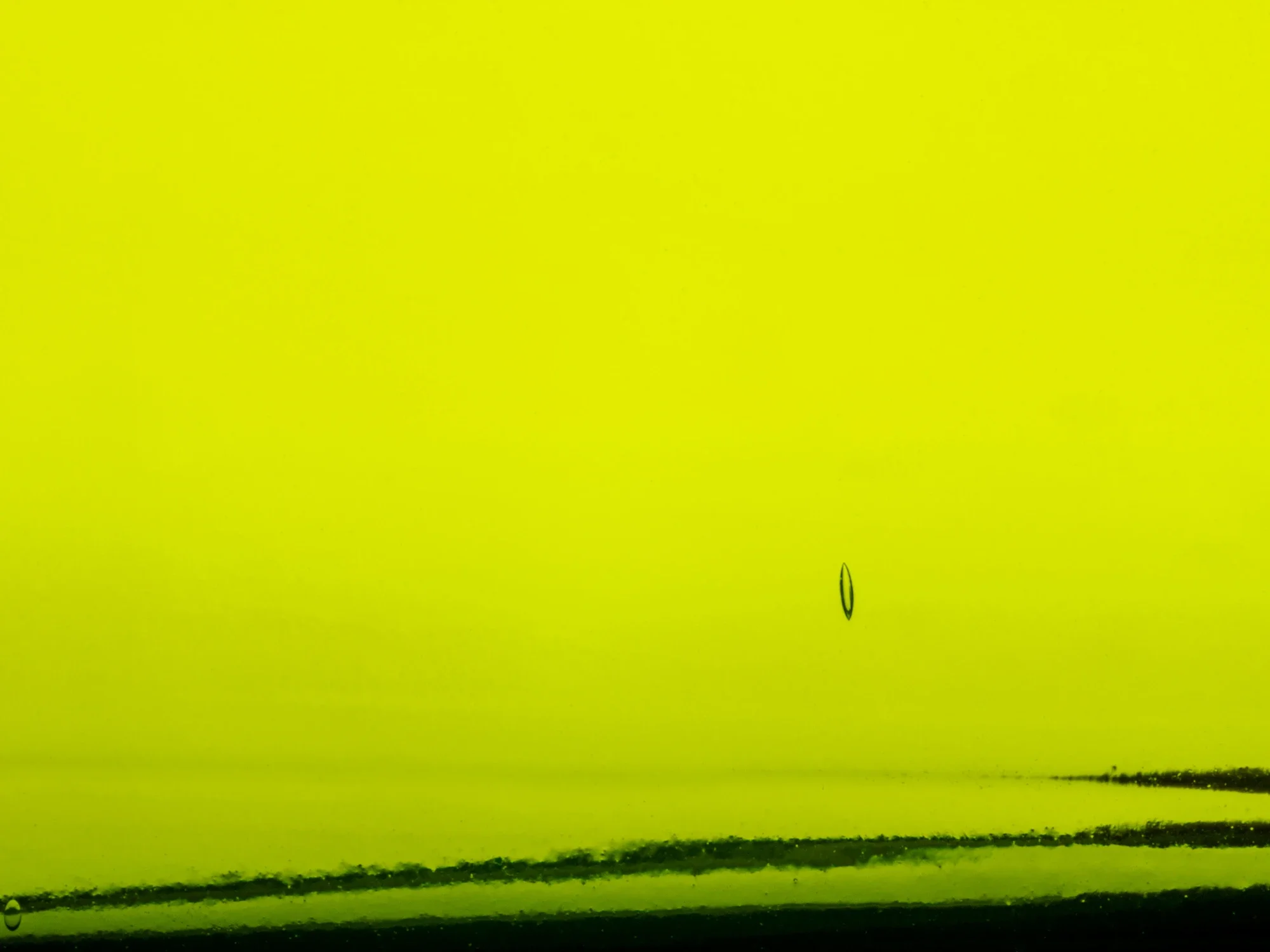 Une image d'une feuille de papier jaune avec des marques noires, et deux petites ellipses noires.