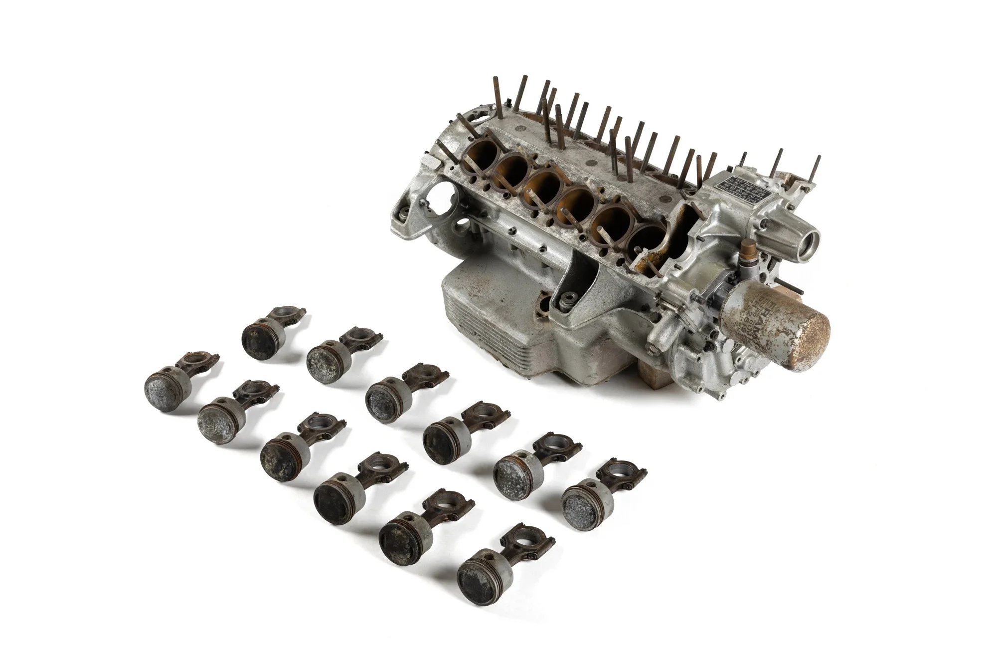 Moteur de voiture décomposé avec pistons et vilebrequin, pièces de moteur disposées sur un fond blanc.