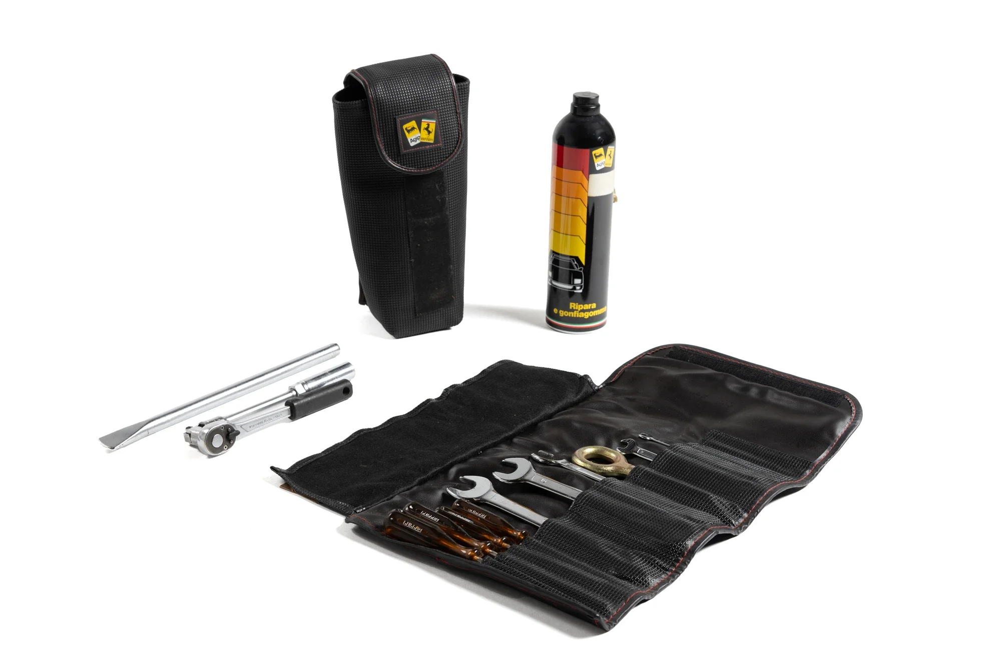 Kit d'outils comprenant un étui à outillage, une bouteille de réparation, une clé de roue, plusieurs tournevis, un levier de pneu, et d'autres outils dissimulés dans un sac ouvert.