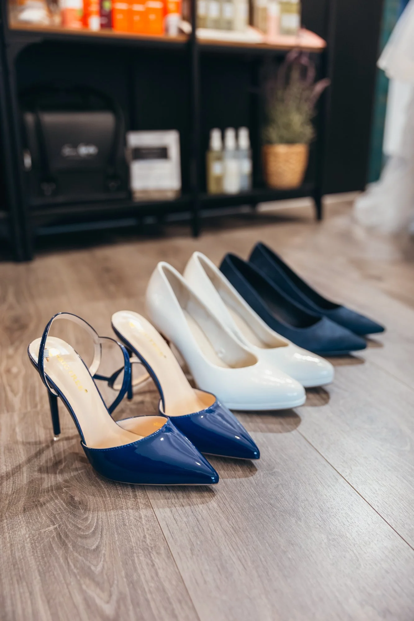 Une rangée de chaussures à talons aiguilles, en bleu, blanc et noir, alignées sur un sol en bois