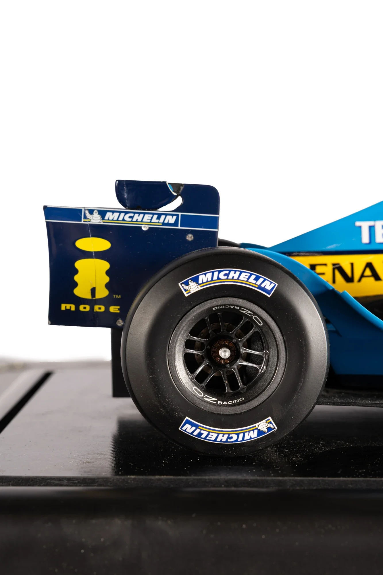 Une partie d'une voiture de course de Formule 1, montrant une roue arrière avec les logos Michelin et Renault, et une partie de l'aileron arrière avec le logo Michelin.