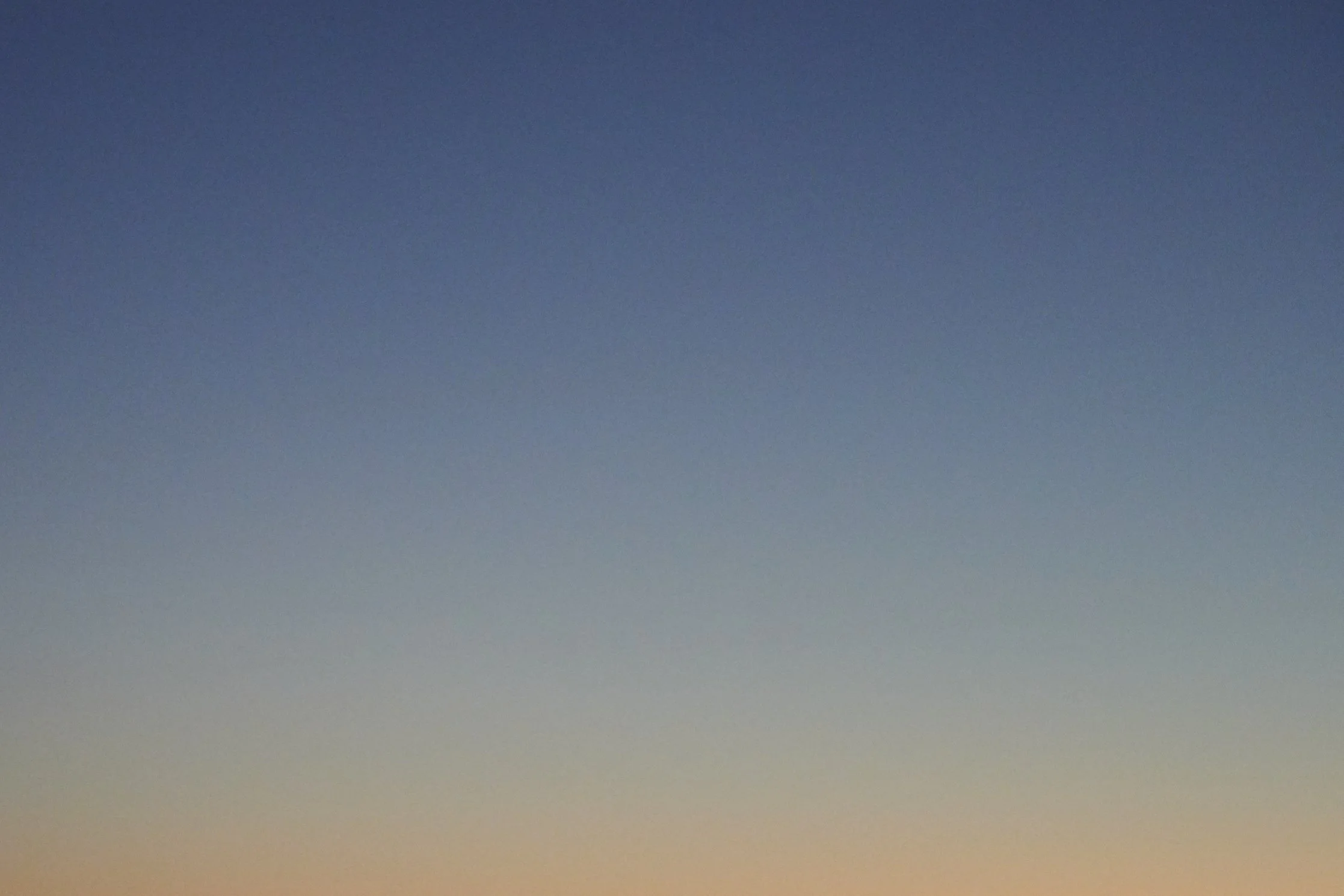 A gradient sky transitioning from dark blue at the top to soft orange at the bottom.