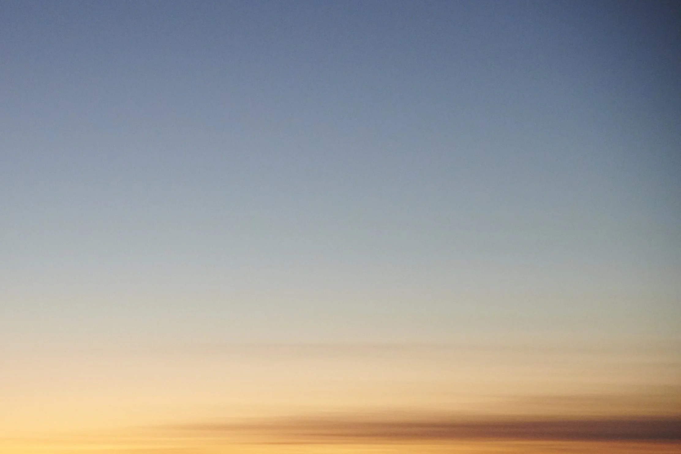 A colorful sunset sky with a gradient of blue, yellow, and orange hues.