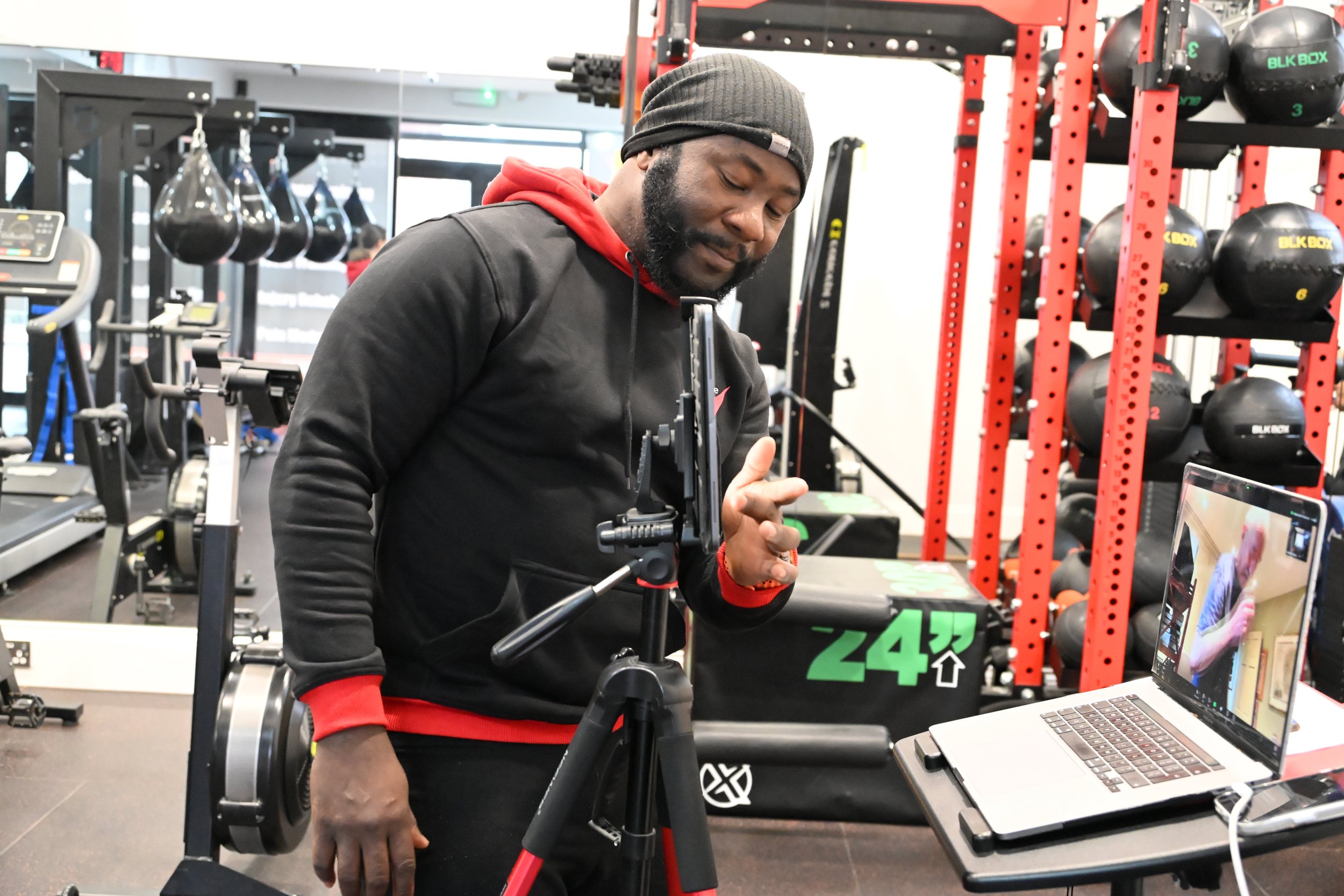 TrainRite founder, Emmanuel, doing an online session with a client, with exercise equipment in the background.