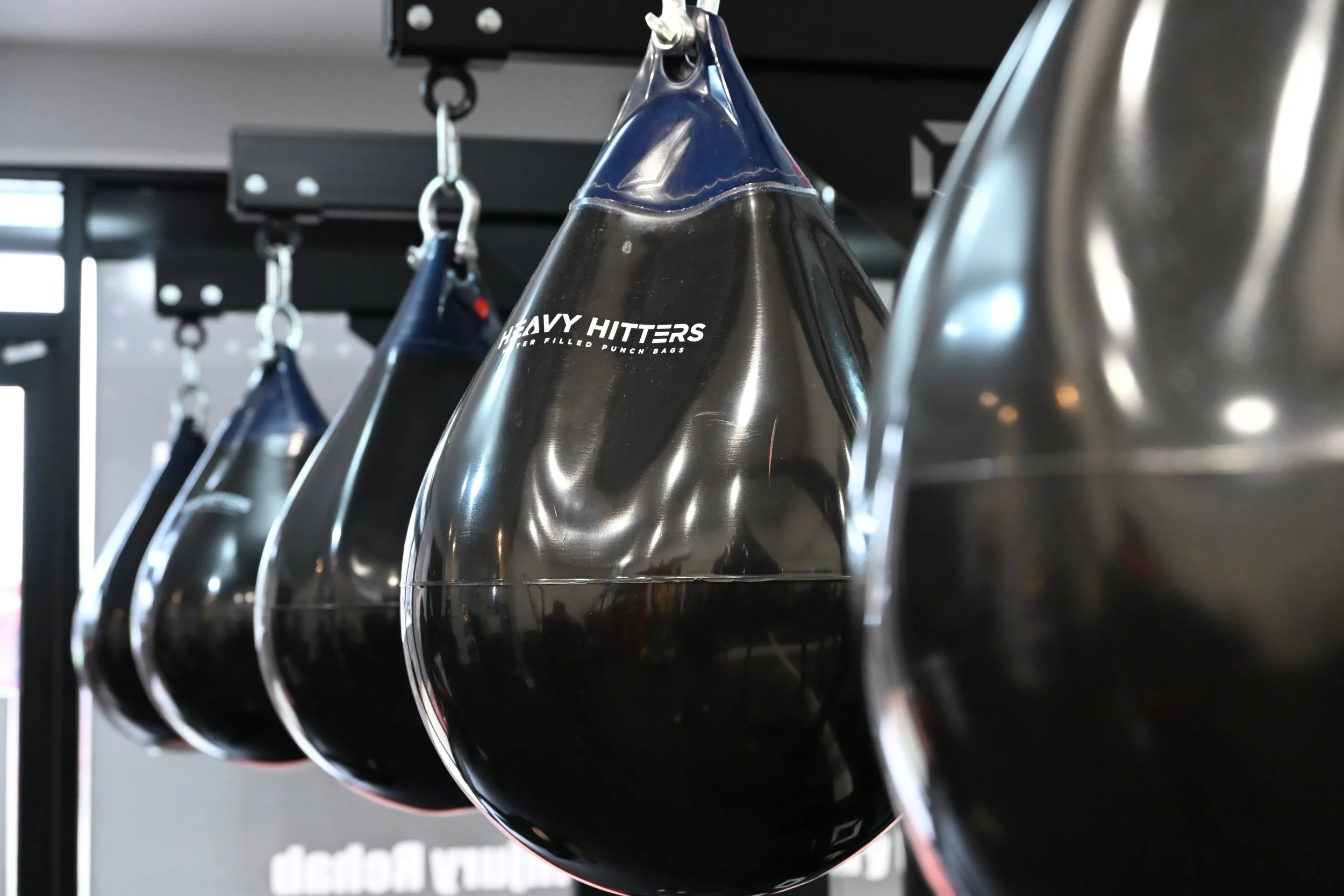 Black boxing punching bags hanging in a gym.
