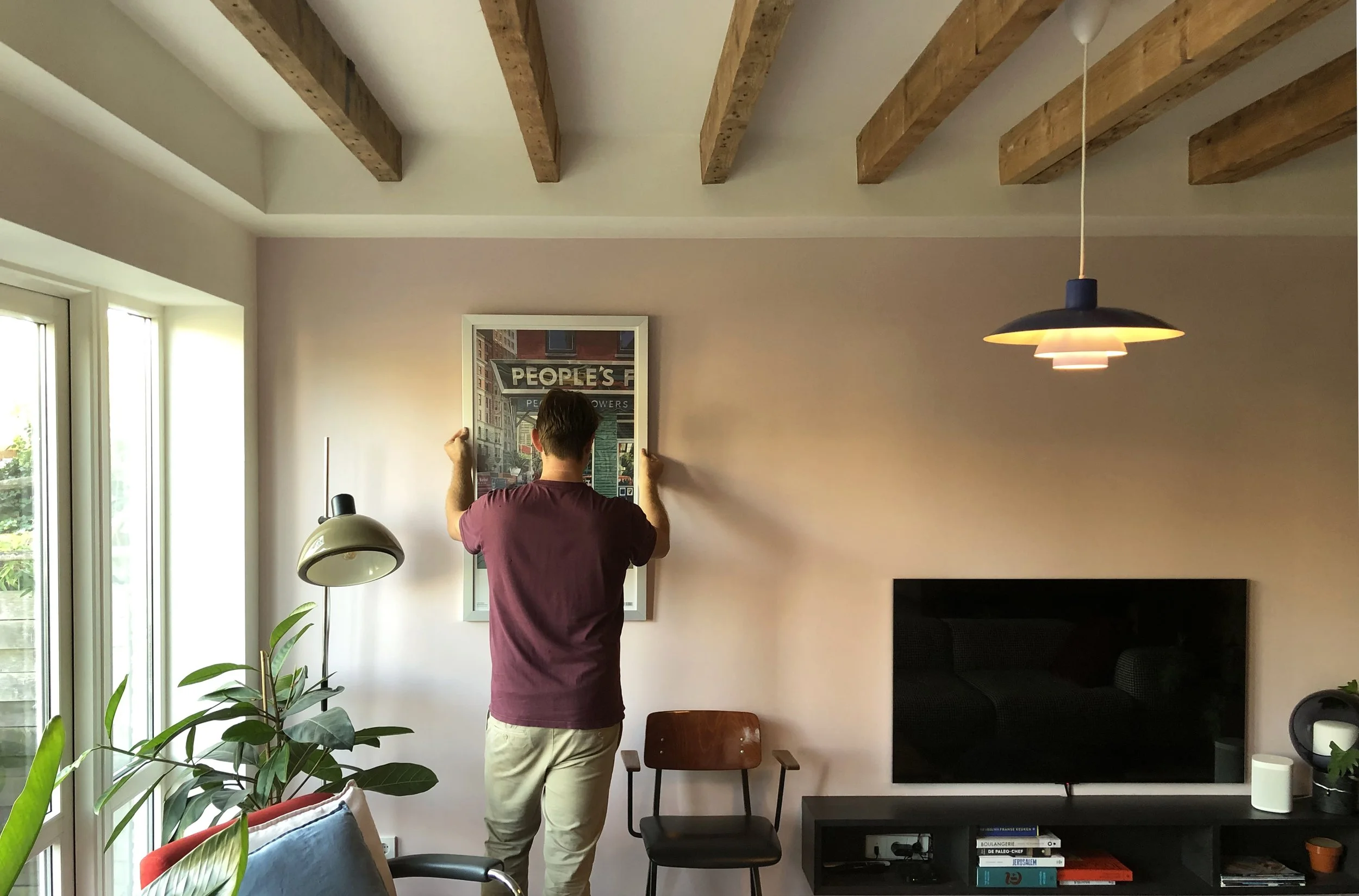 Zitkamer van de duurzame woning in Rotterdam. Frisse kleuren en veel daglichtinval in de ruimte. Het karakteristieke balkenplafond is prominent zichtbaar.