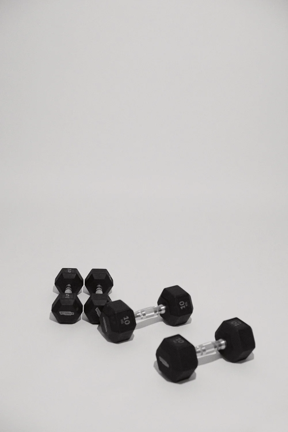Four pairs of black and gray dumbbells of different weights on a plain white background.