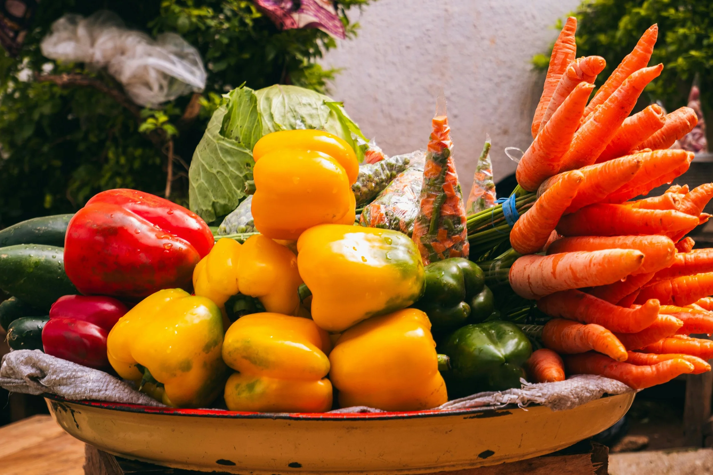 Basket of fresh peppers, carrots, and other vegetables at a farmer's market.