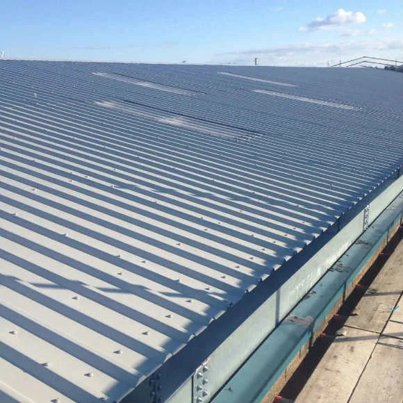 Close-up of a large, silver, corrugated metal rooftop on a building, with shadows cast by the sunlight.