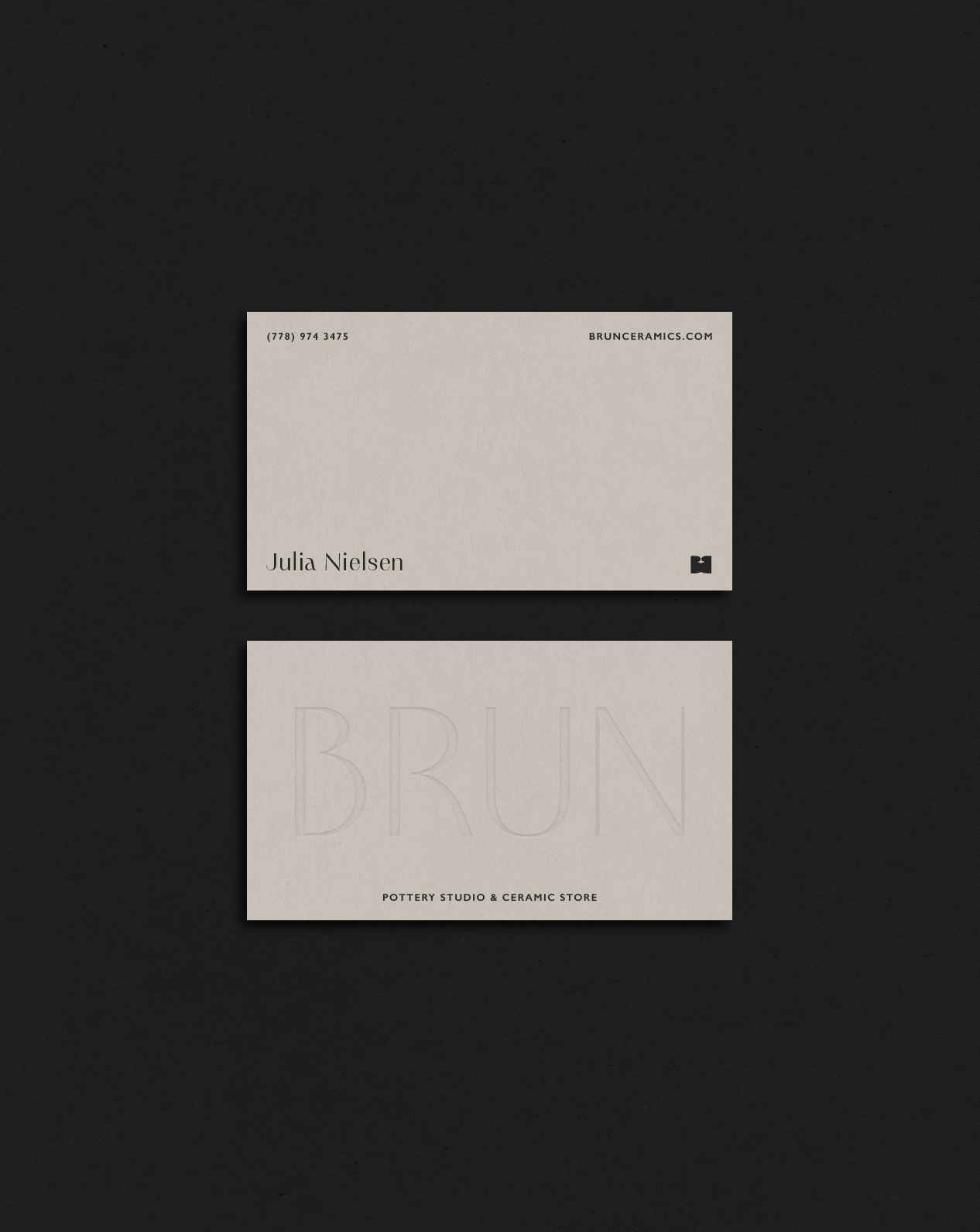Business cards for Julia Nielsen and Brun Pottery Studio & Ceramic Store placed on a black surface.