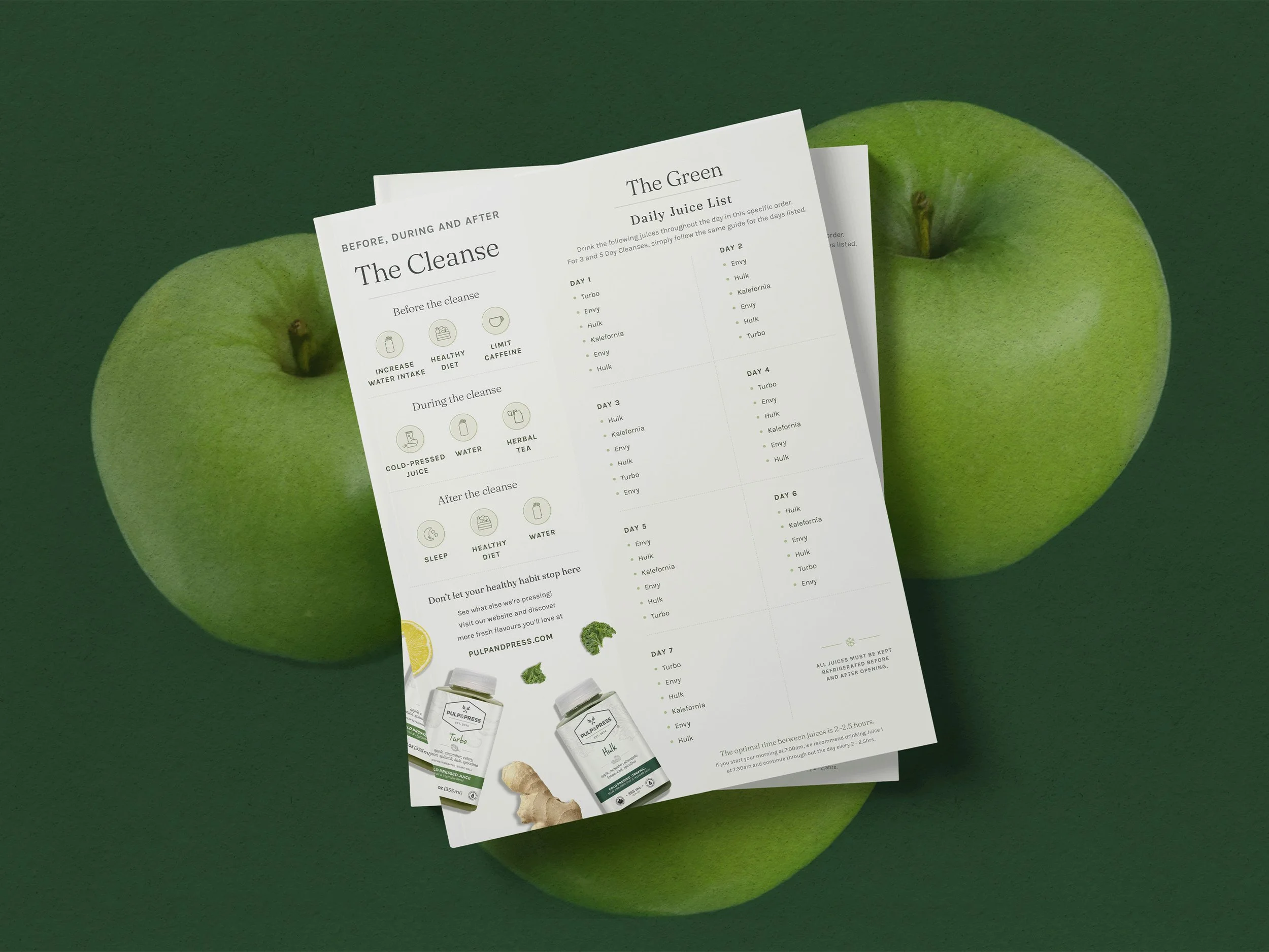 A paper flyer titled "The Cleanse" listing steps for a juice cleanse, with sections for before, during, and after, alongside a green apple, ginger, and herbal tea on a green background.