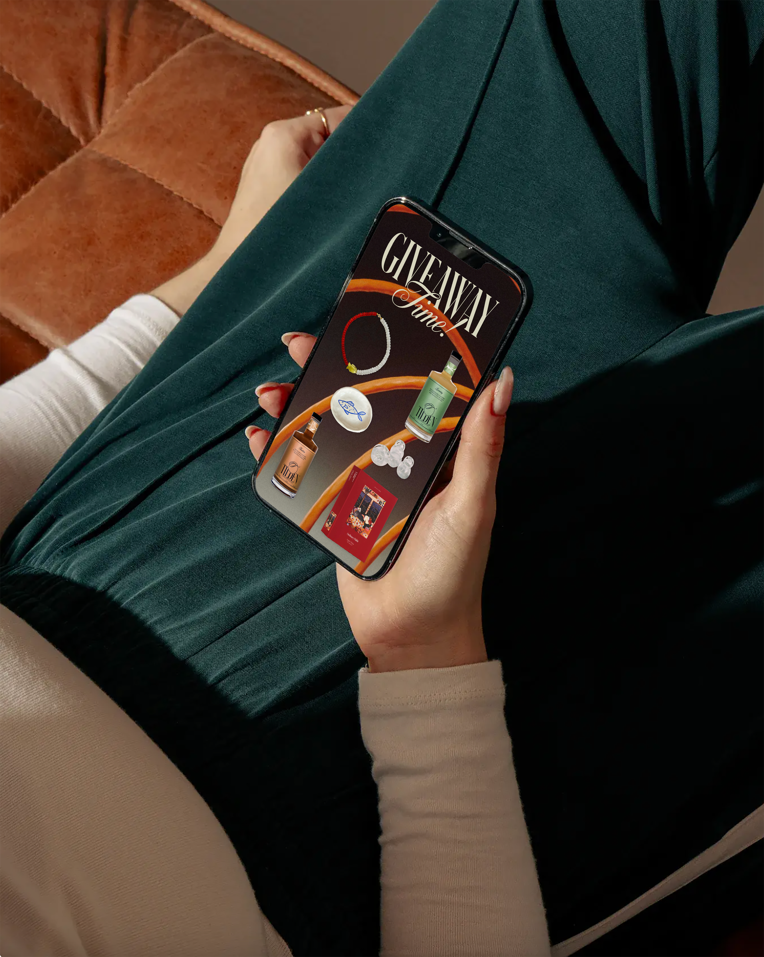 Person sitting on a couch holding a smartphone displaying an app with giveaway prizes, including bottles, jewelry, a book, and a bracelet.