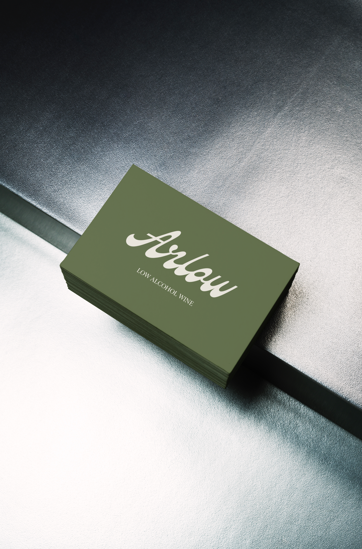 A stack of green cards with the words 'Aloha LOW ALCOHOL WINE' printed on them. The cards are resting on a textured metallic surface.