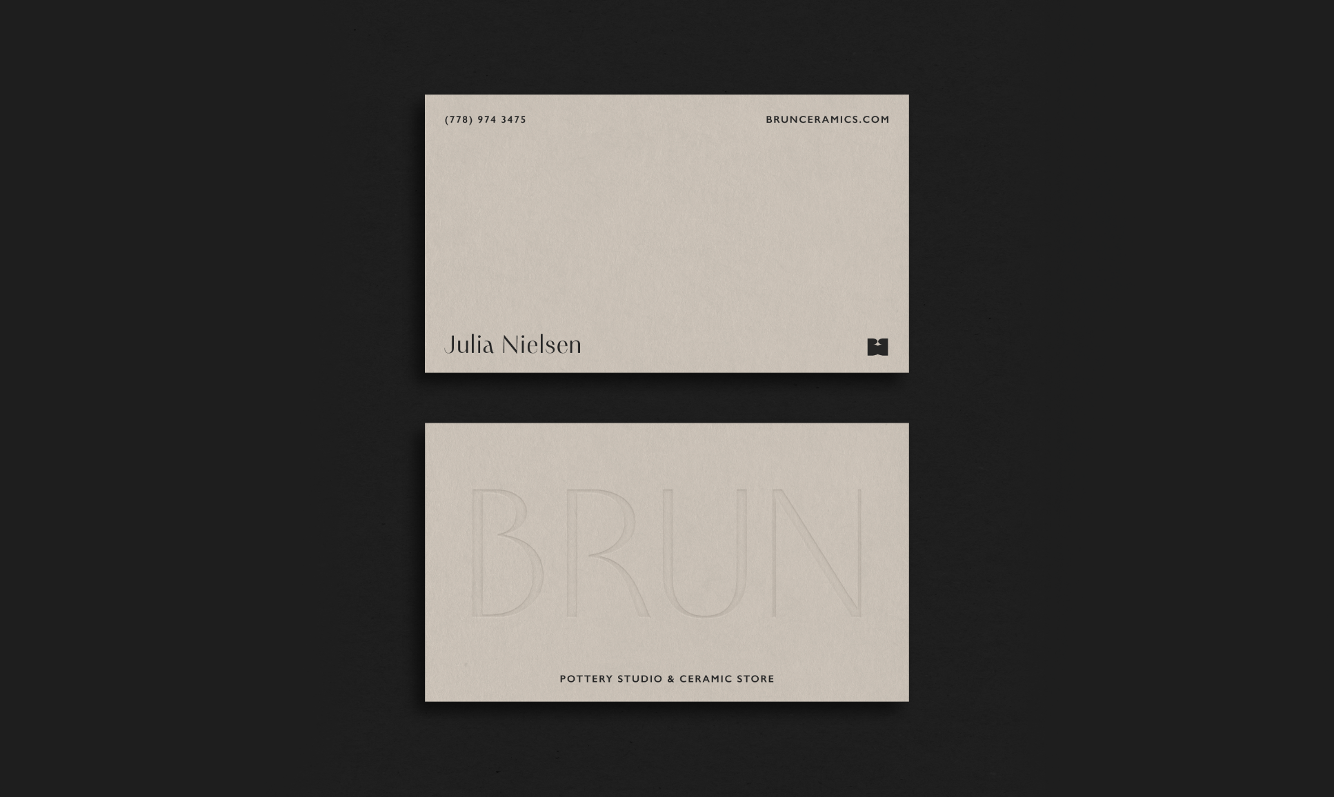 A minimalist business card design with the name Julia Nielsen, contact information, and website at the top, and an embossed logo with the word 'BRUN' and the text 'Pottery Studio & Ceramic Store' at the bottom, set against a dark background.