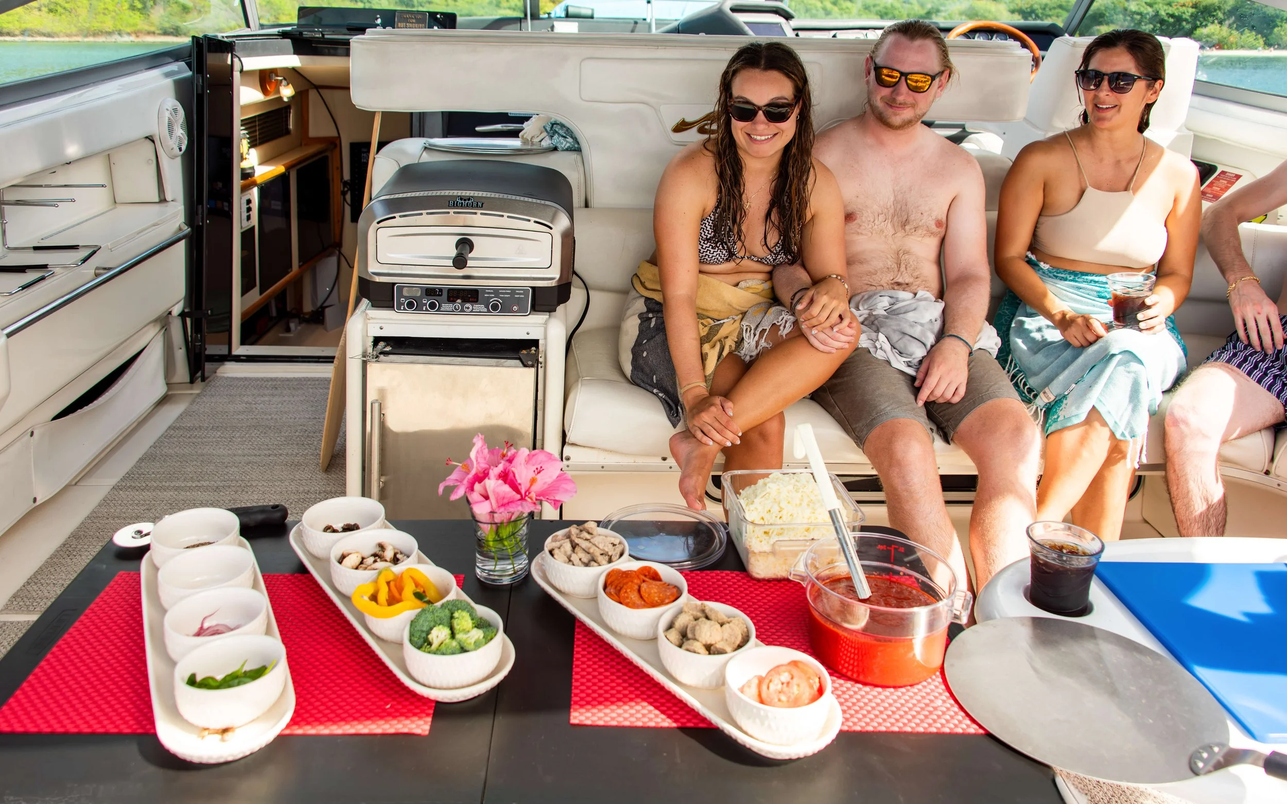 People enjoying a meal on a boat with various dishes and drinks on the table.