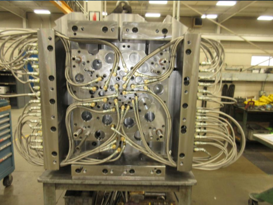 Industrial metal mold with multiple tubes and wires in a manufacturing facility.