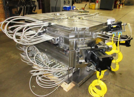 Industrial machine with numerous cables and yellow safety cords in a manufacturing setting.