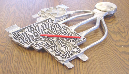 A maze puzzle in the shape of the United States with a red stick inside, placed on a wooden surface.