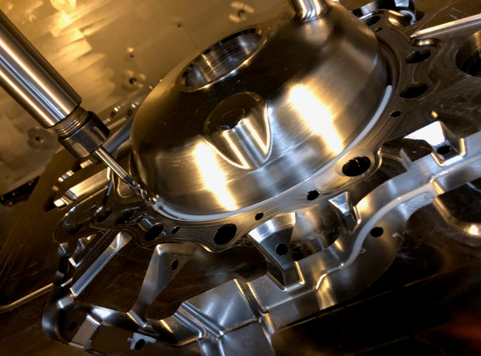 Close-up of a shiny, metallic aircraft engine component with a drill bit preparing to modify or assemble it.