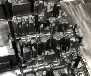 Close-up of a metallic engine cylinder head with multiple valve stems and bolt holes.