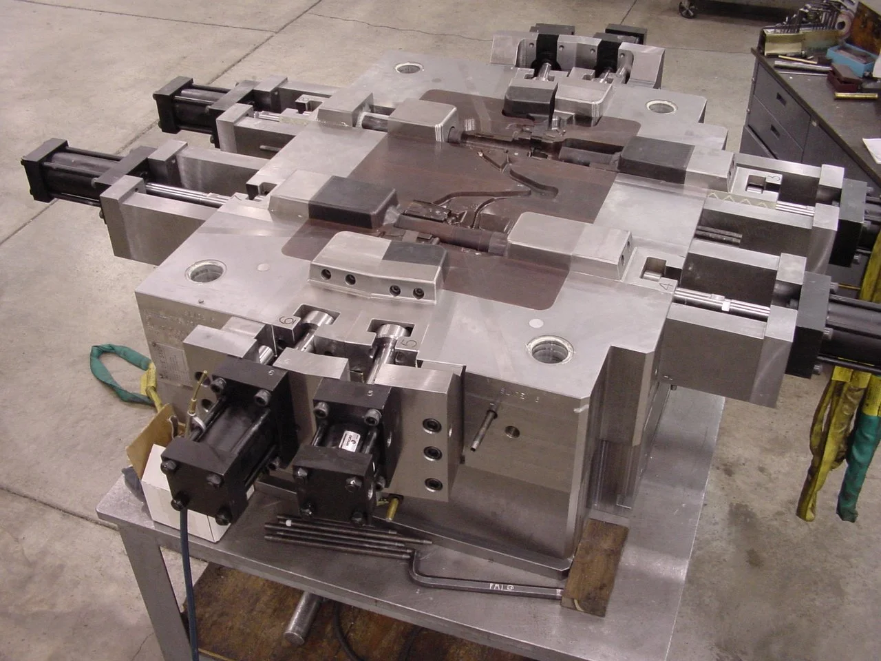 Large industrial metal mold or die on a worktable in a factory setting.