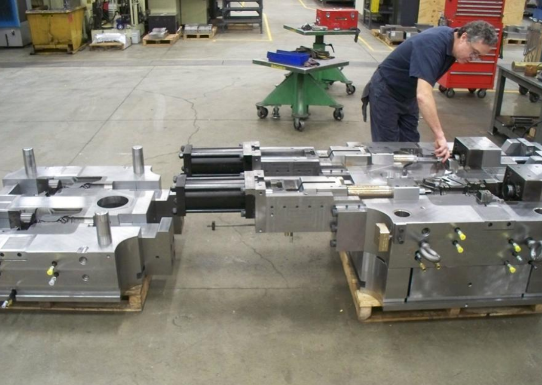 A worker assembling or inspecting a large metal machinery component in a factory workshop.