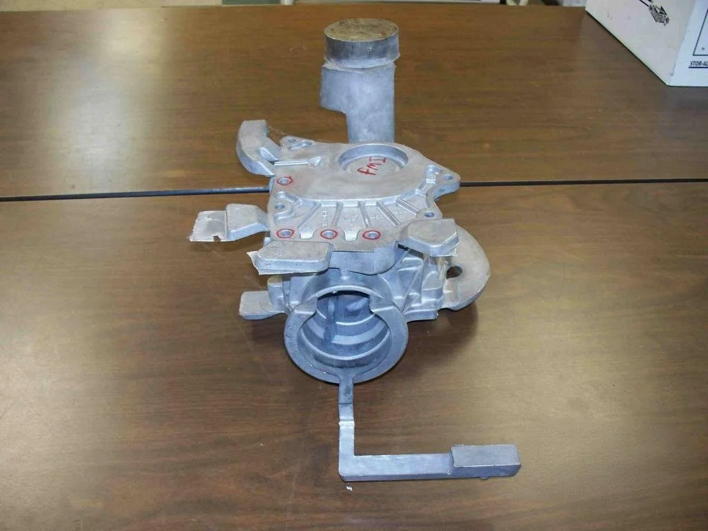 Metal automotive engine component placed on a wooden table.