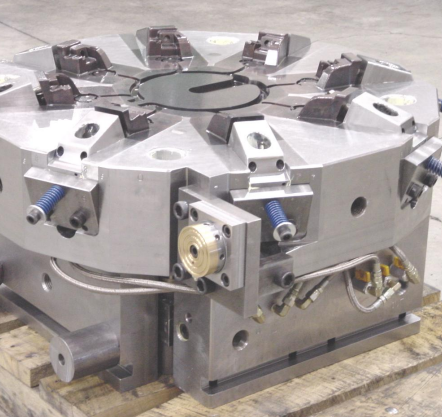 Metal industrial mold or die with multiple components and screws, resting on a wooden pallet.